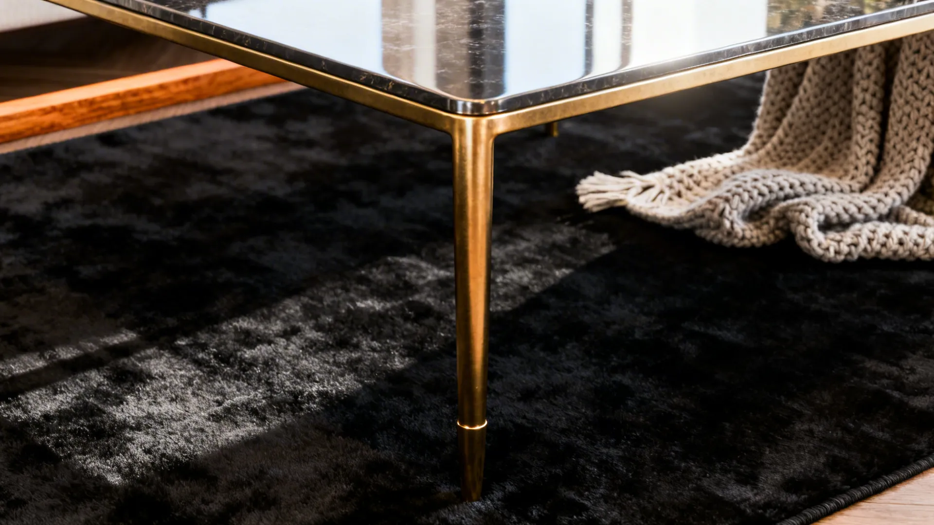 Velvety black rug under a brass-legged coffee table with warm textiles