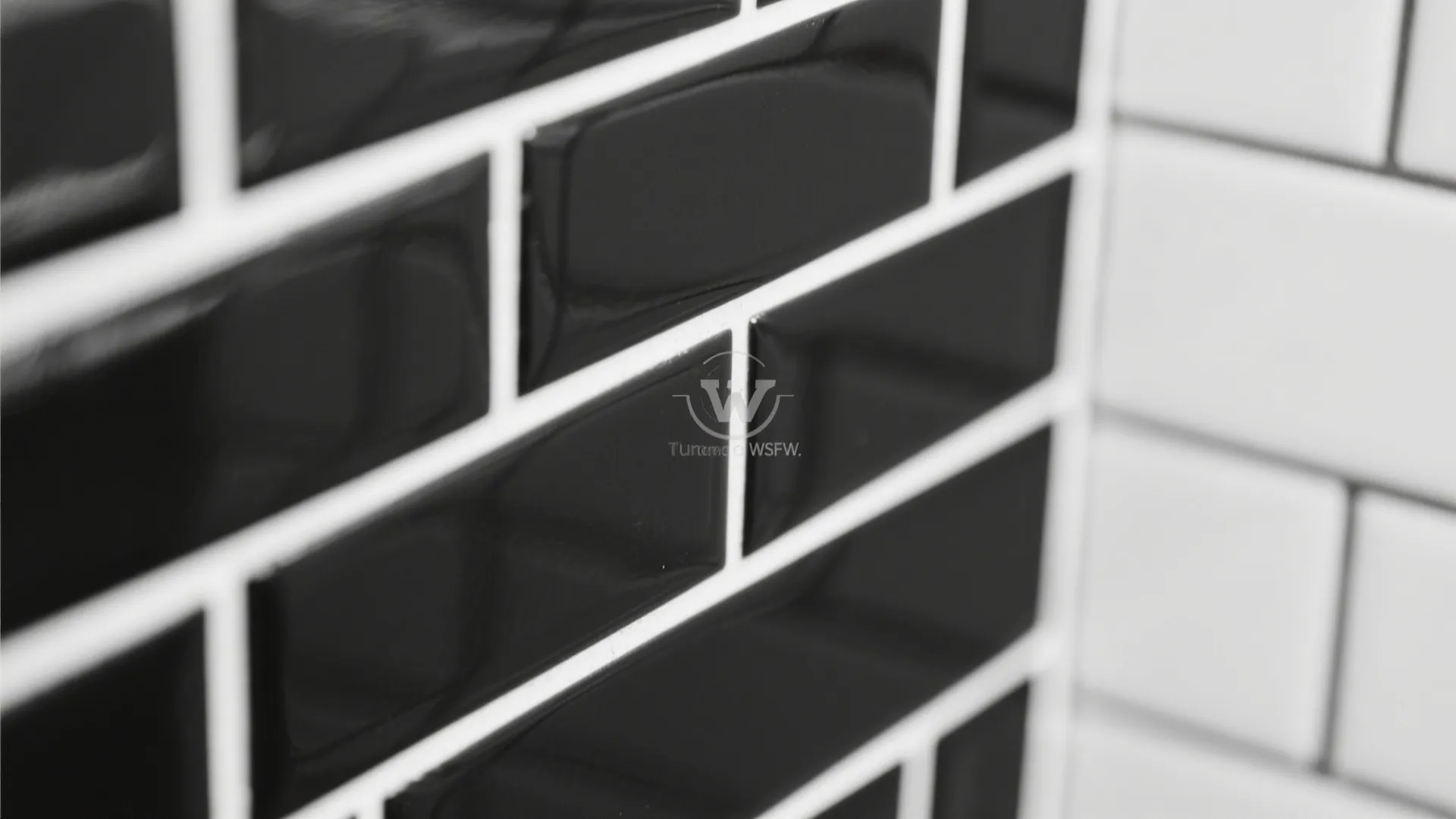 Close up of glossy black brick wall tiles with white grout lines in a modern bathroom