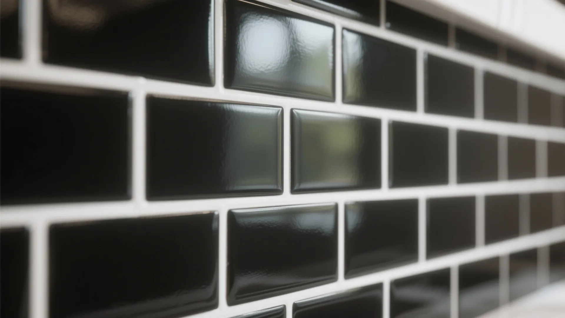 Close up of glossy black rectangular wall tiles with white grout in a modern kitchen