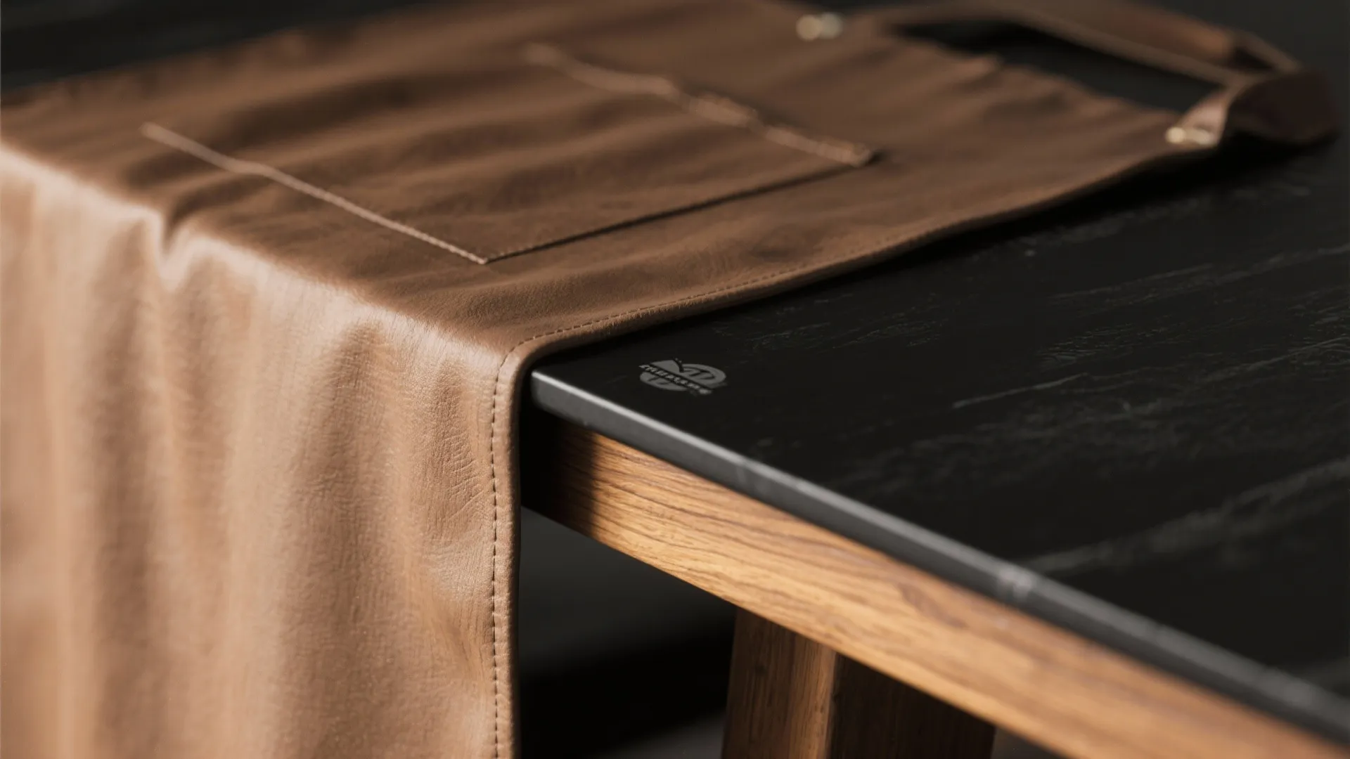 Detail of a matte black tabletop with natural wood apron showing grain and joinery.