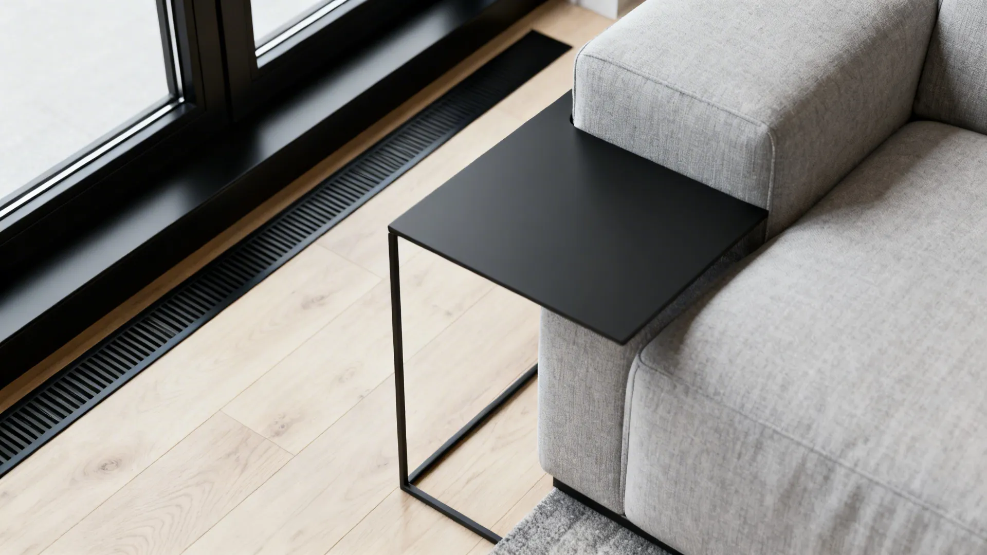 Close up of a grey sofa with a minimalist black metal side table on wood flooring