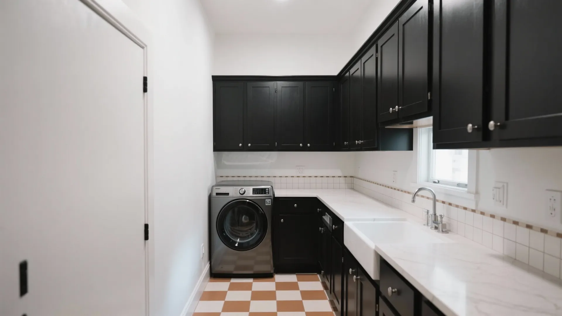 Modern laundry room featuring black cabinets white marble countertops silver washing machine and checkered floor