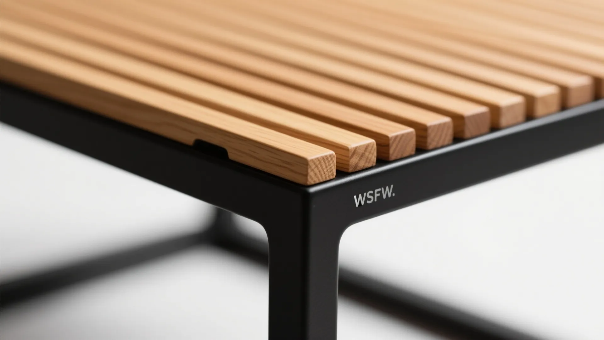 Modern bench showing light wood slats on a black metal frame with a small logo