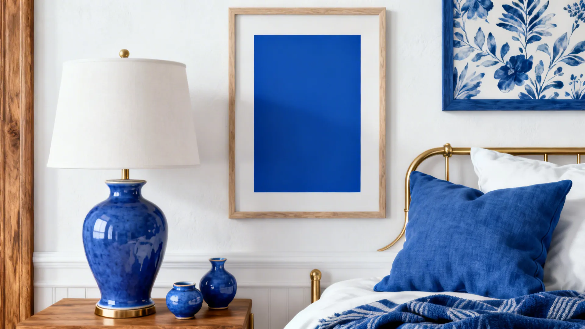 Flatlay of blue and white bedroom accessories including ceramics, pillows, and framed art.