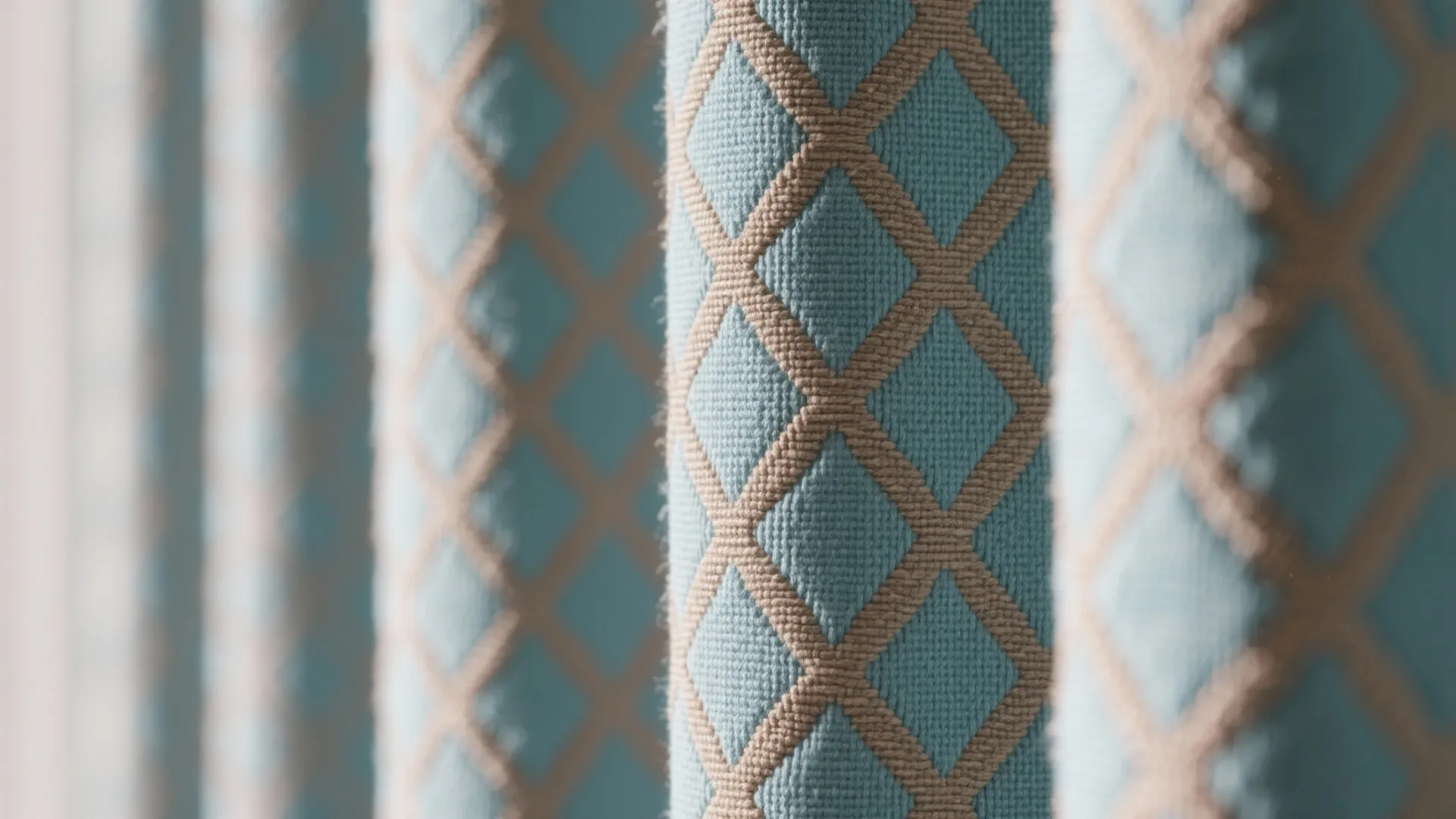 Close up of light blue curtain fabric with brown diamond pattern in a bright room