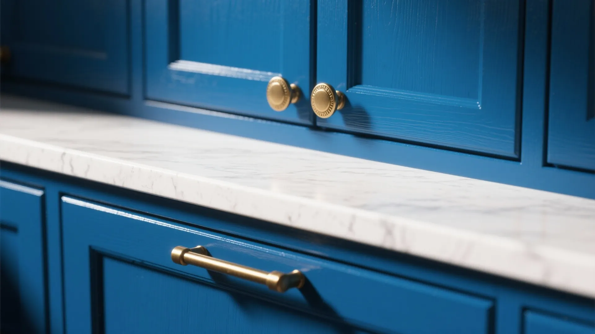 Close up of blue kitchen cabinet with marble countertop and gold handles in modern home interior