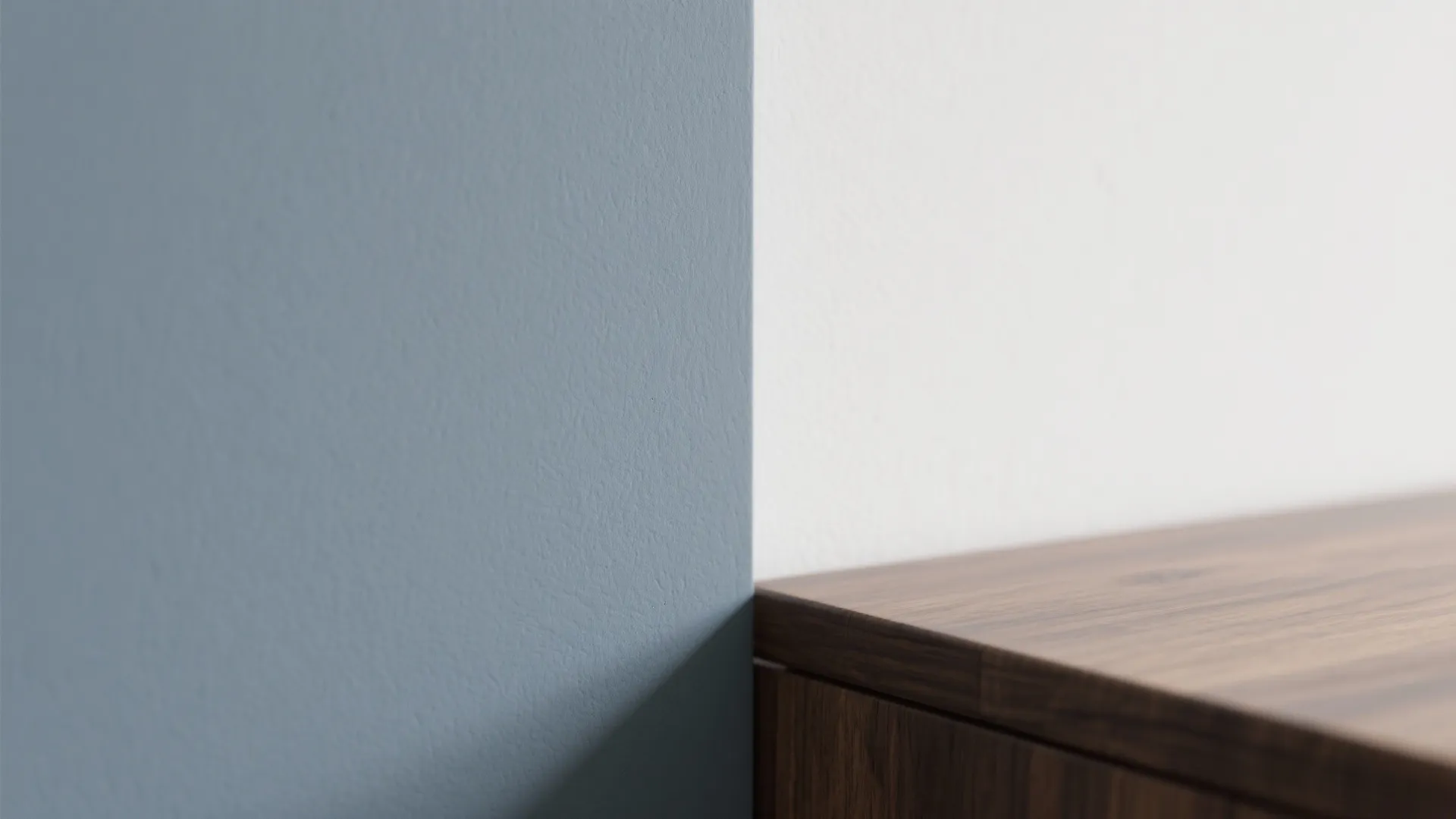 Close up of a dark wood cabinet meeting a light blue wall and white wall