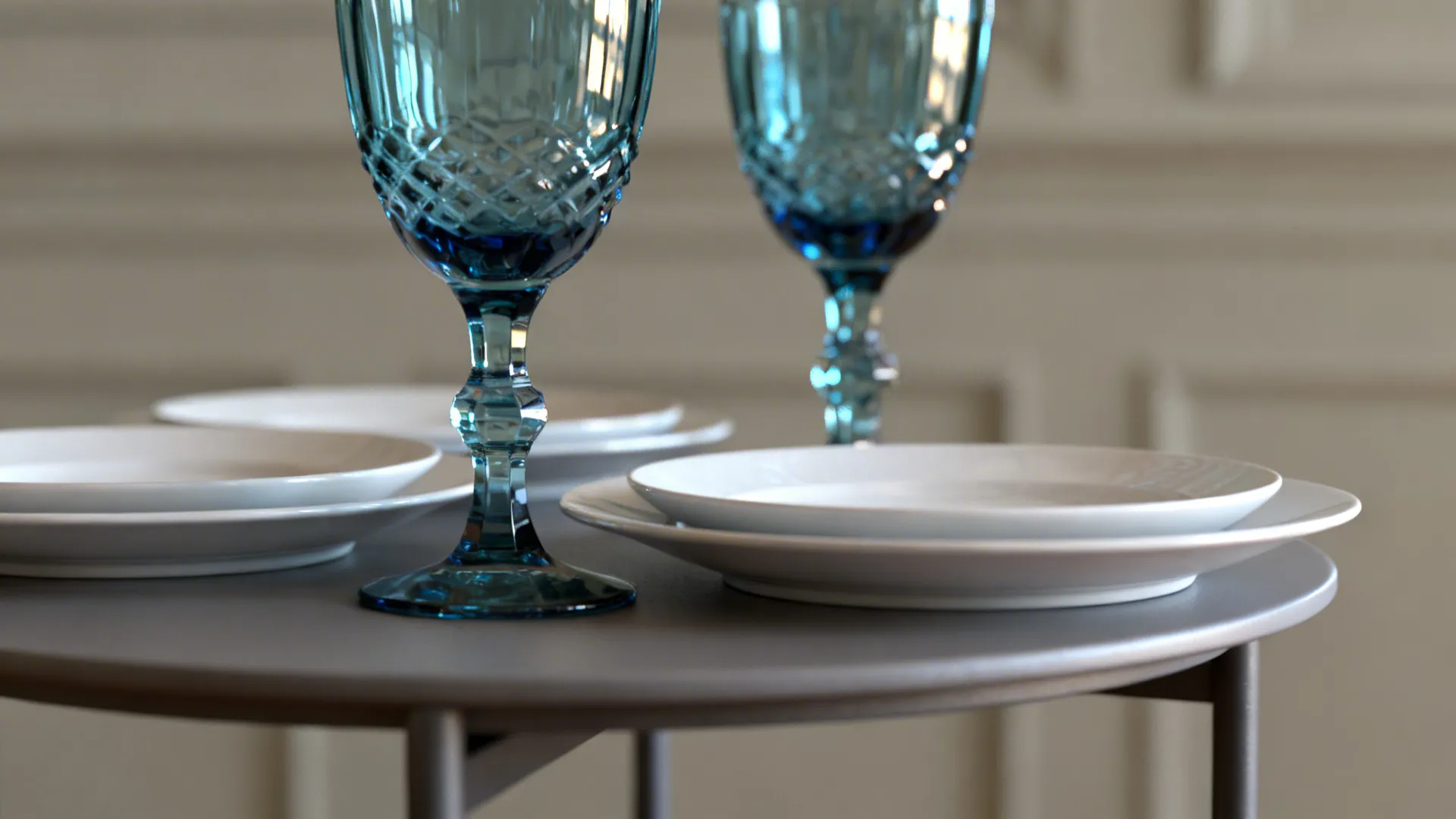 Blue-tinted goblets beside white porcelain plates on a small table