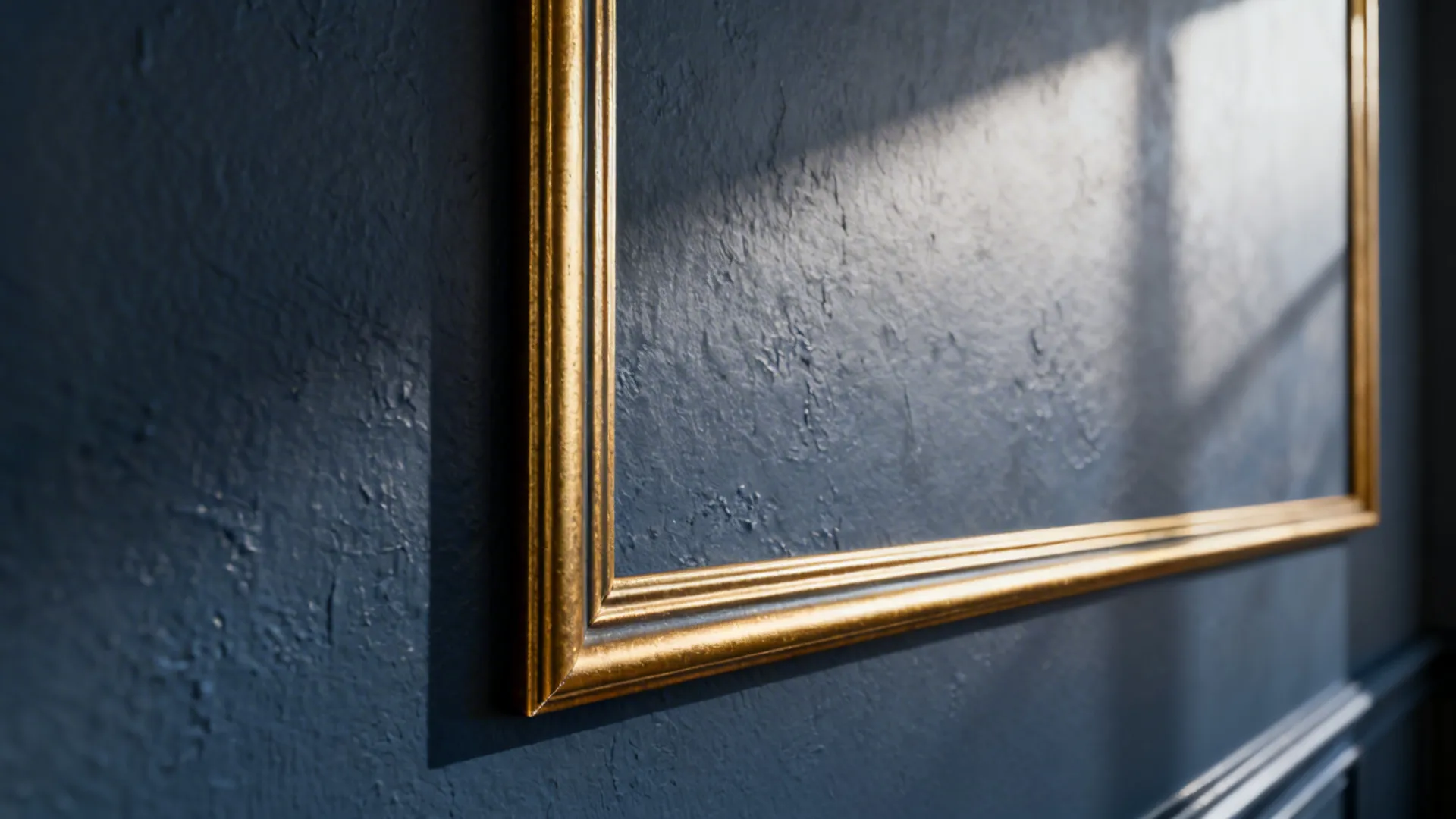 Close-up of deep blue-grey wall with thin gold picture-frame moulding.