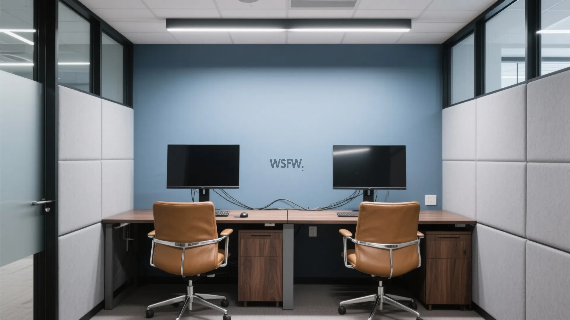 Modern office workspace with blue wall two computer monitors brown leather chairs and wood desks