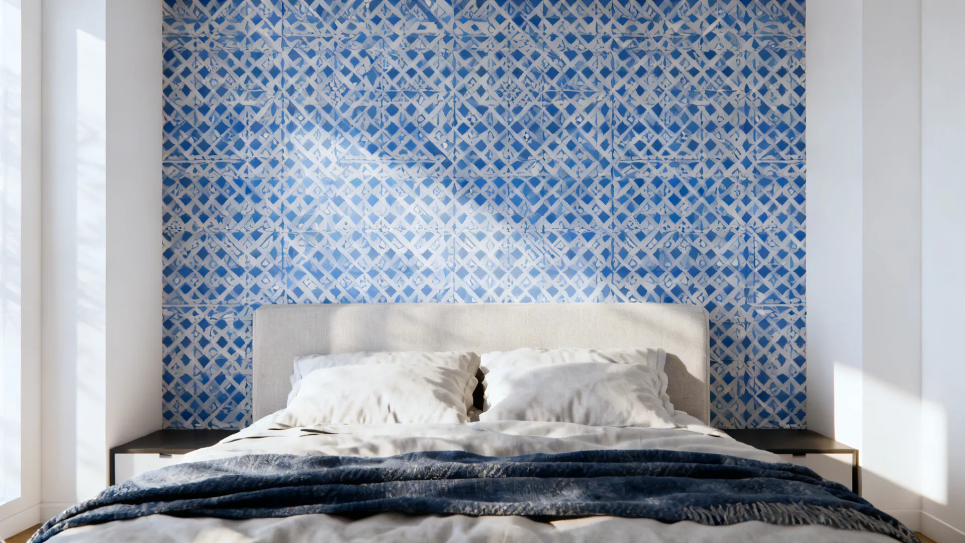 Blue-and-white geometric wallpaper behind a bed with neutral linens.