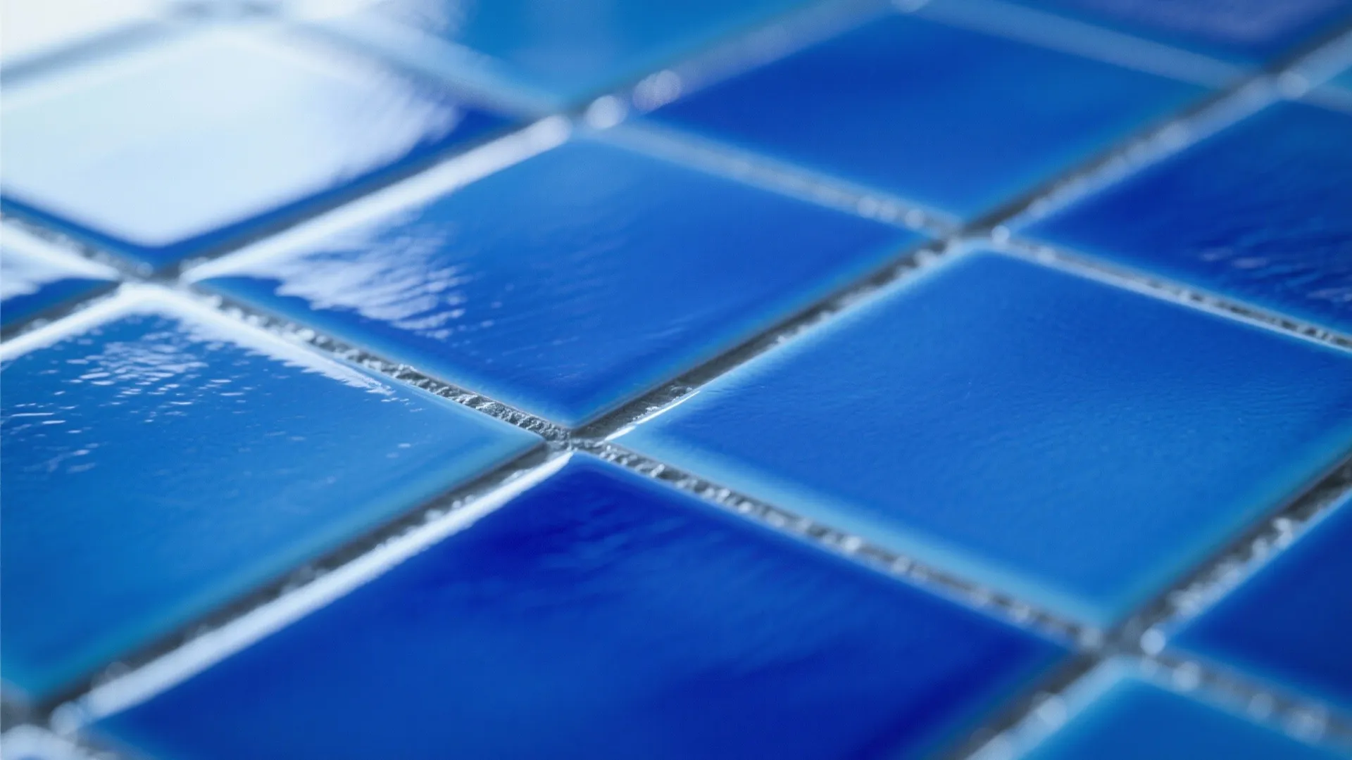 Close up view of bright blue square wall tiles with light grey grout in bathroom