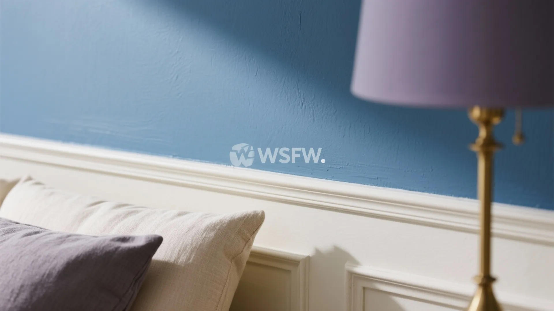 Close-up of blue painted wall featuring white wall panel decorative molding with purple table lamp