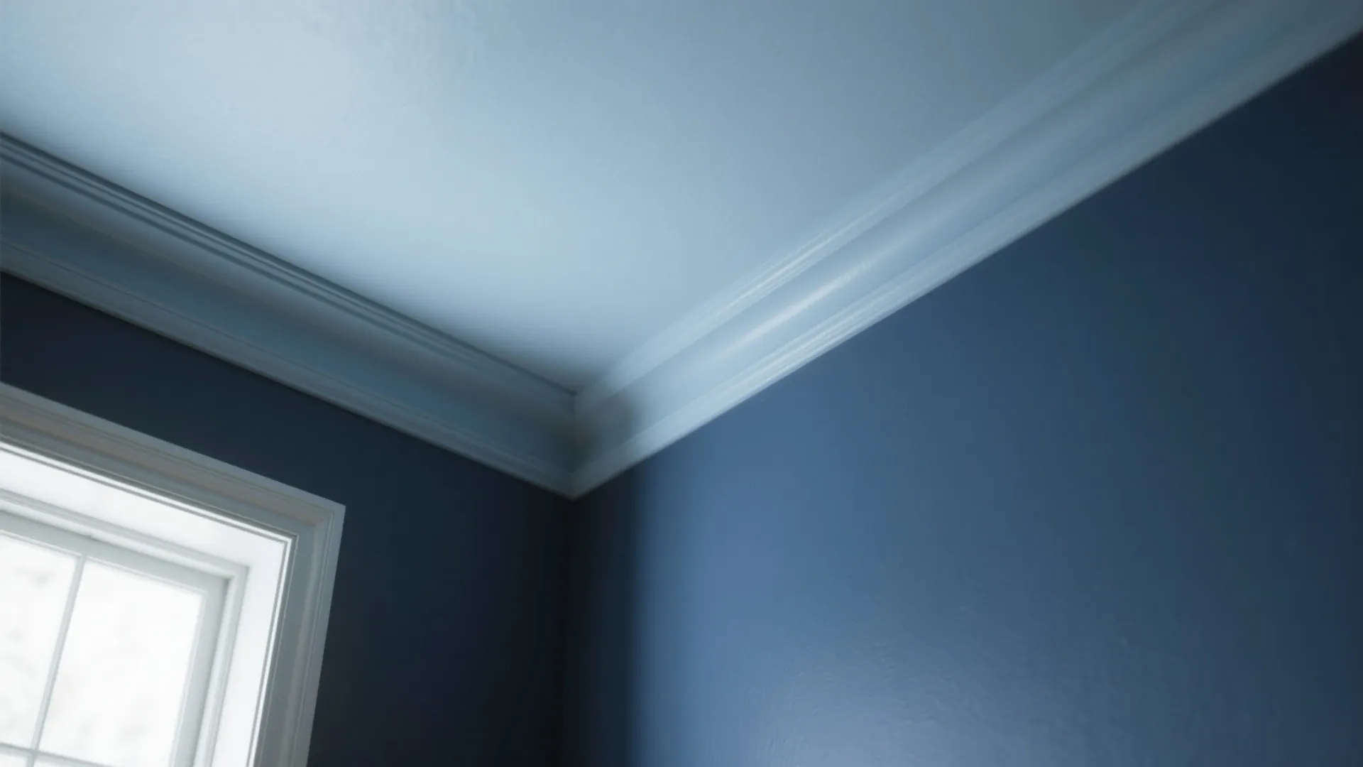 Detail of blue-grey ceiling and trim meeting a navy wall, showing paint texture and molding.