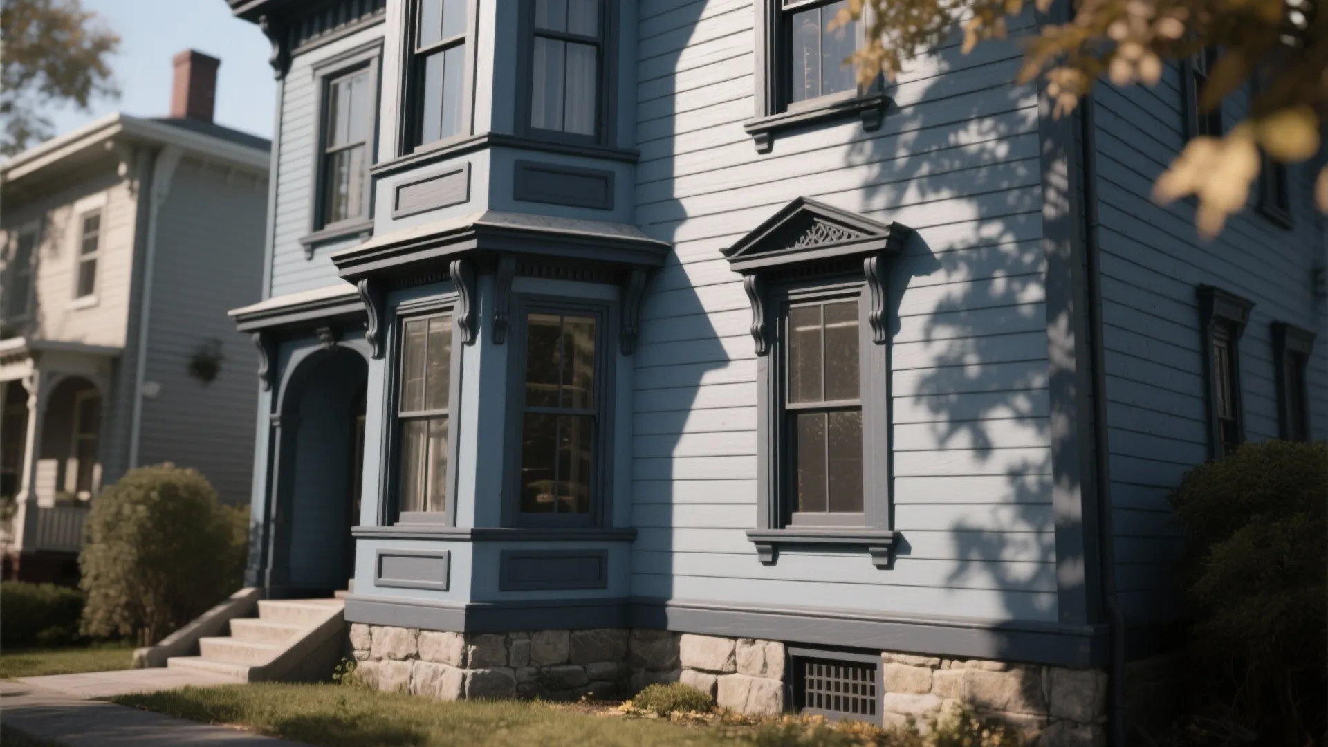 Exterior of a light blue house with dark blue trim and multiple windows in sunlight