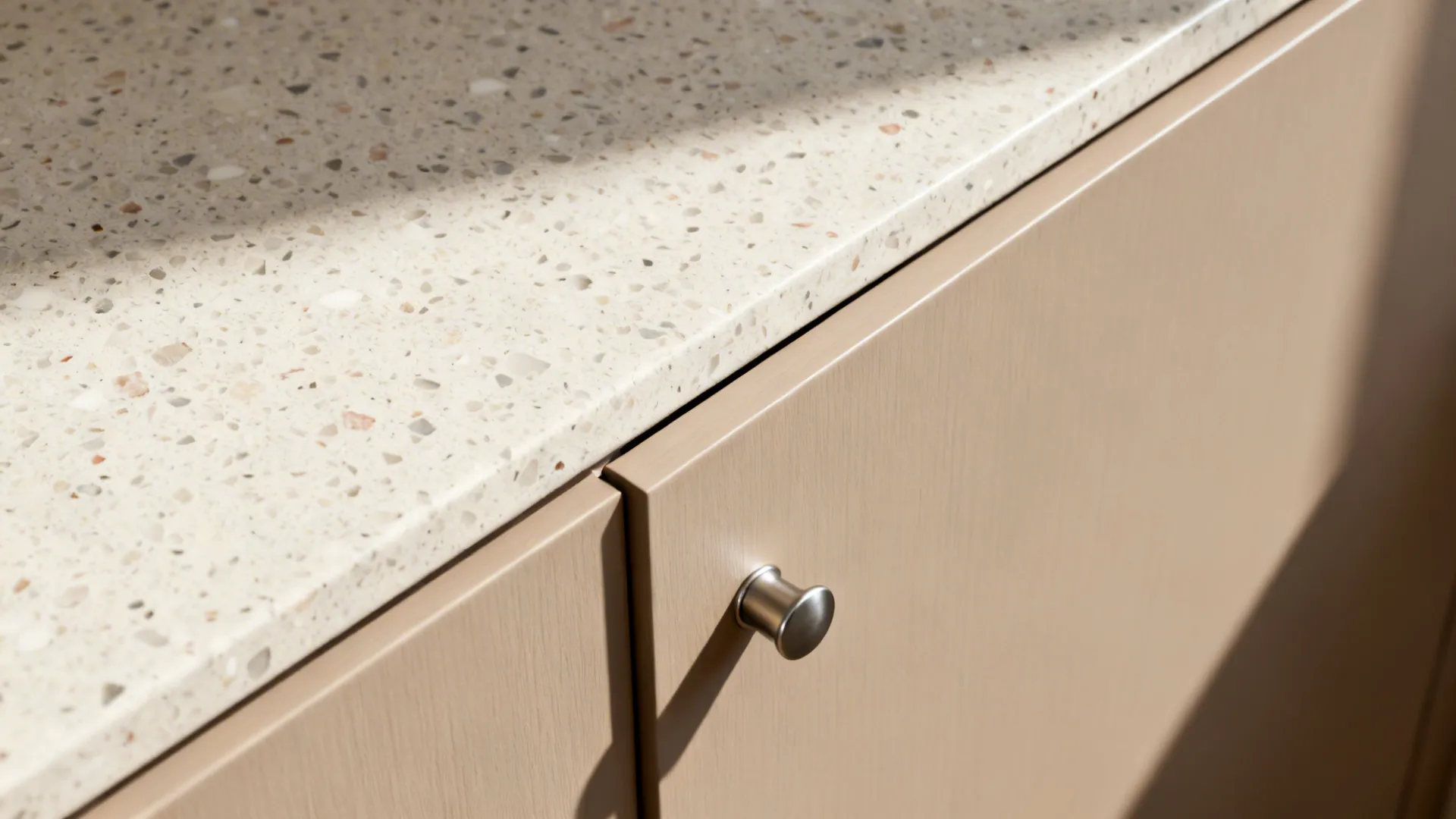 Macro detail of matte blush cabinet edge with satin nickel pull and terrazzo top.