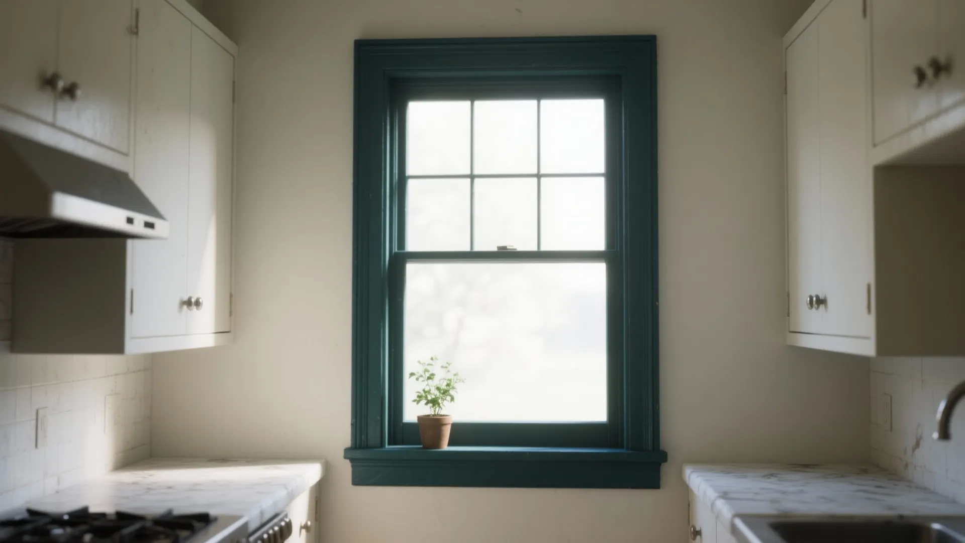 White kitchen cabinets around a window with dark blue frame marble countertops and potted plant
