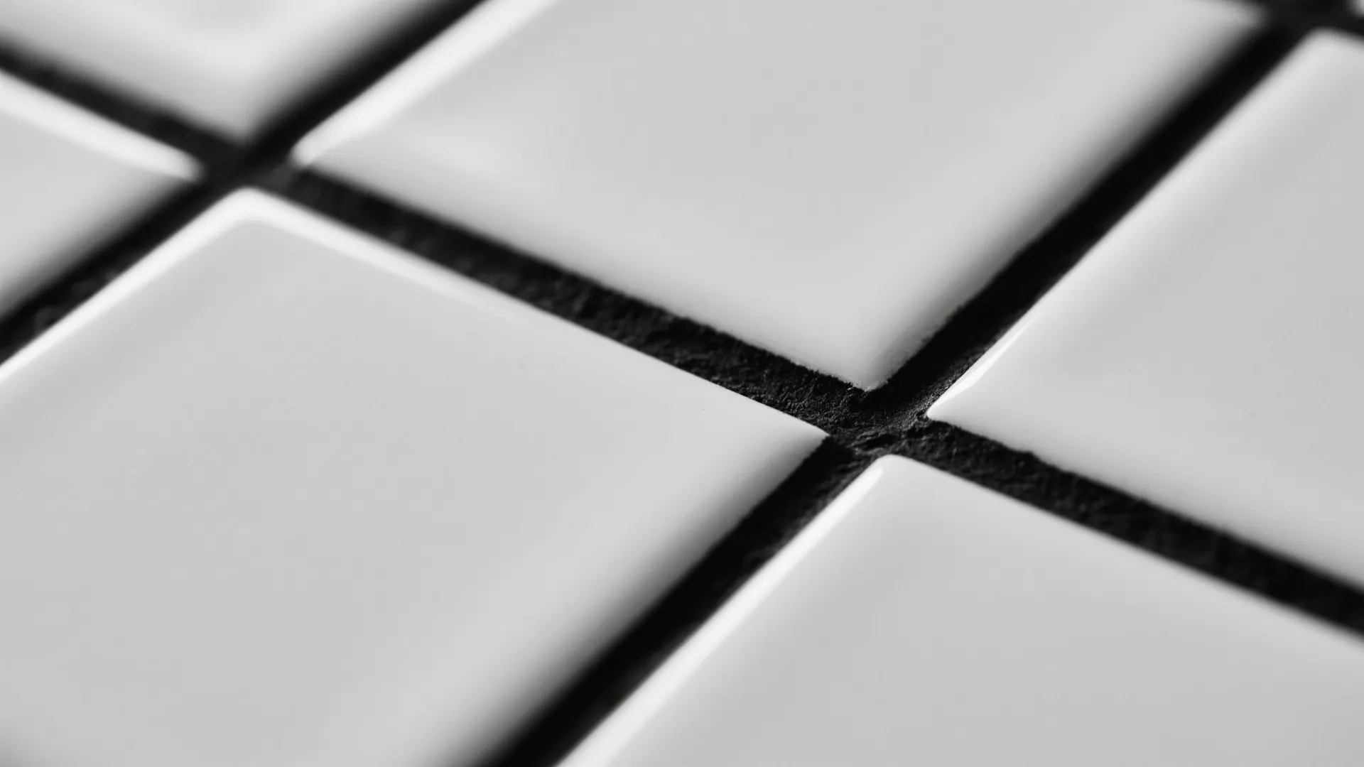 Close up view of white square bathroom tiles with thick black grout lines and glossy finish