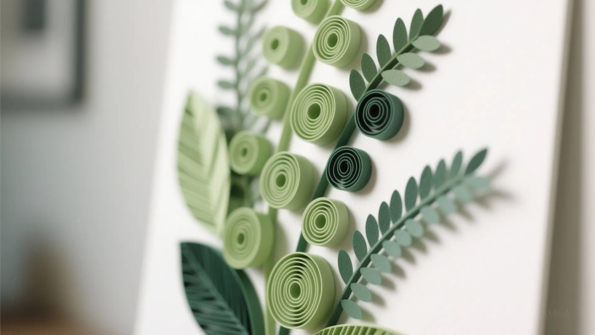 Close up of green paper art showing rolled circles and leaves on a white background