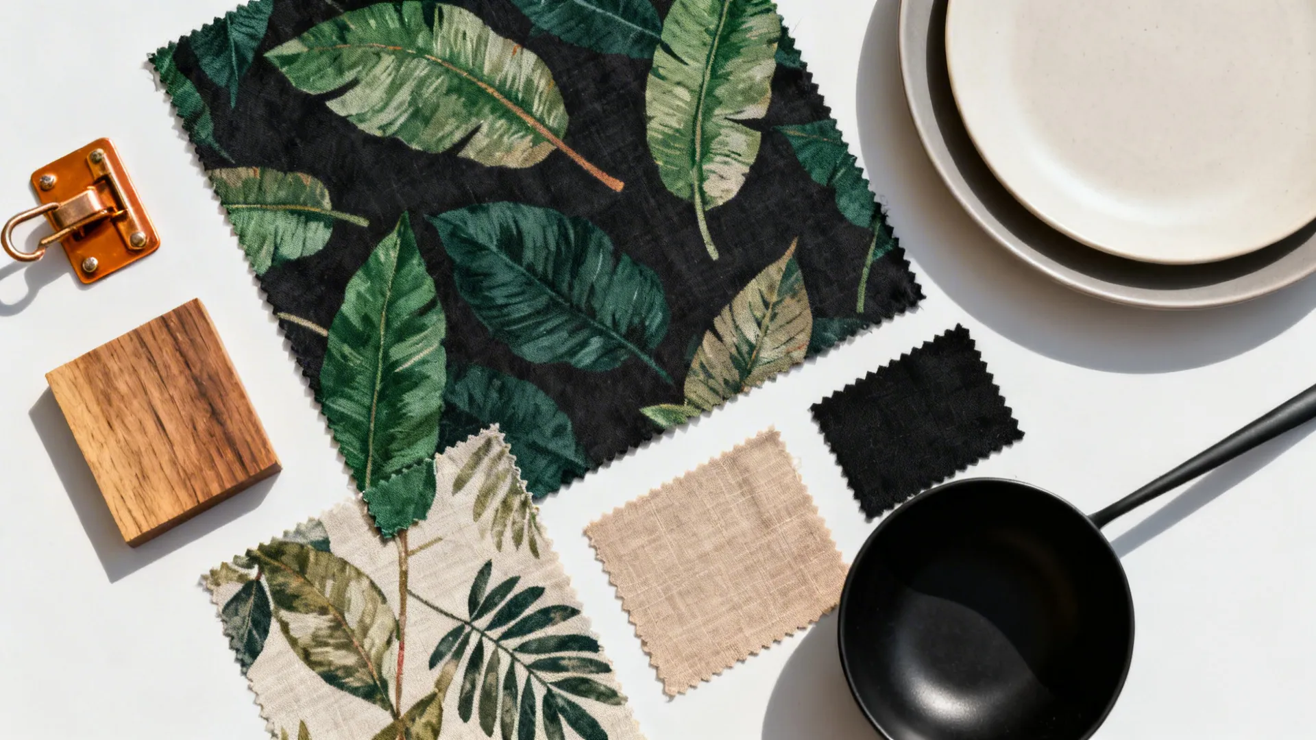 Top-down fabric swatches of dark-ground botanical prints with tableware and wood finish samples.