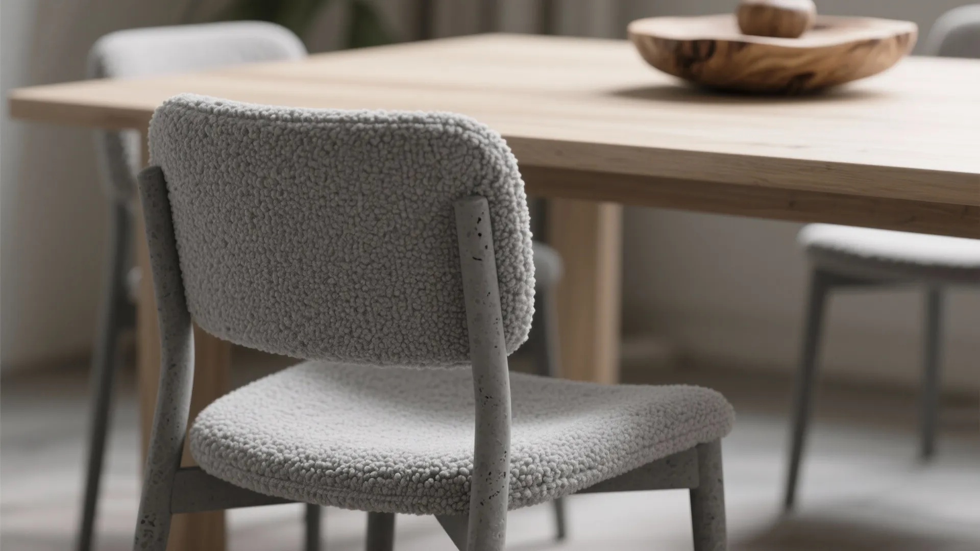 Close up of grey textured dining chair with concrete frame near wooden table and bowl