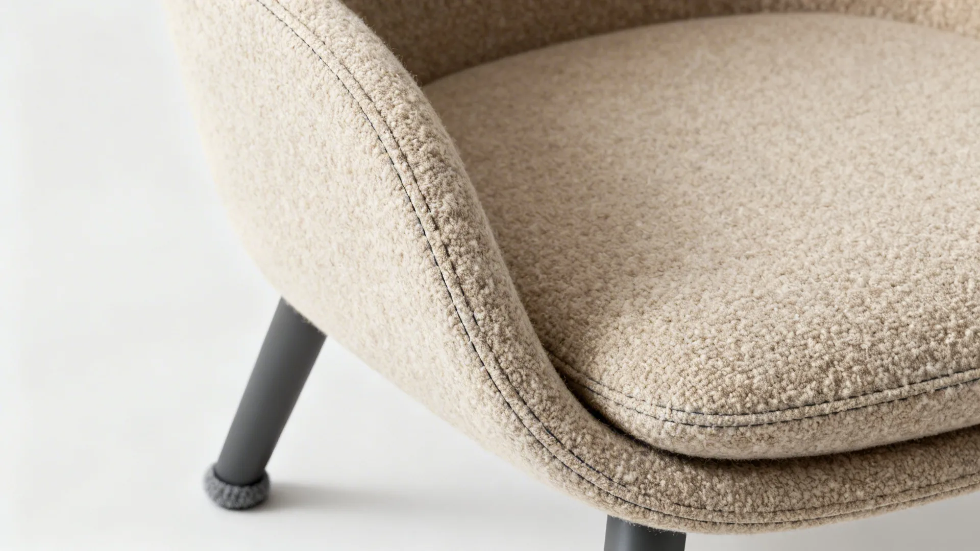 Close up of a soft beige fabric chair with textured material and dark metal legs