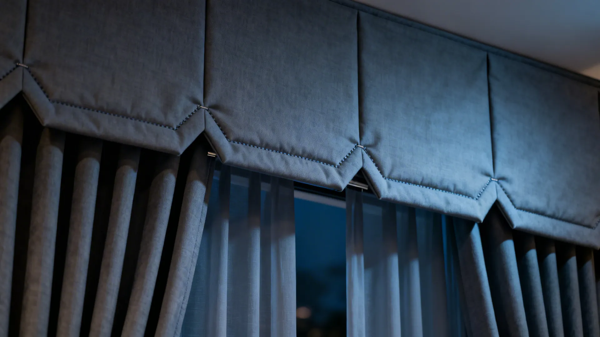 Close up of grey pleated curtain top hanging over thin sheer white curtains in the room