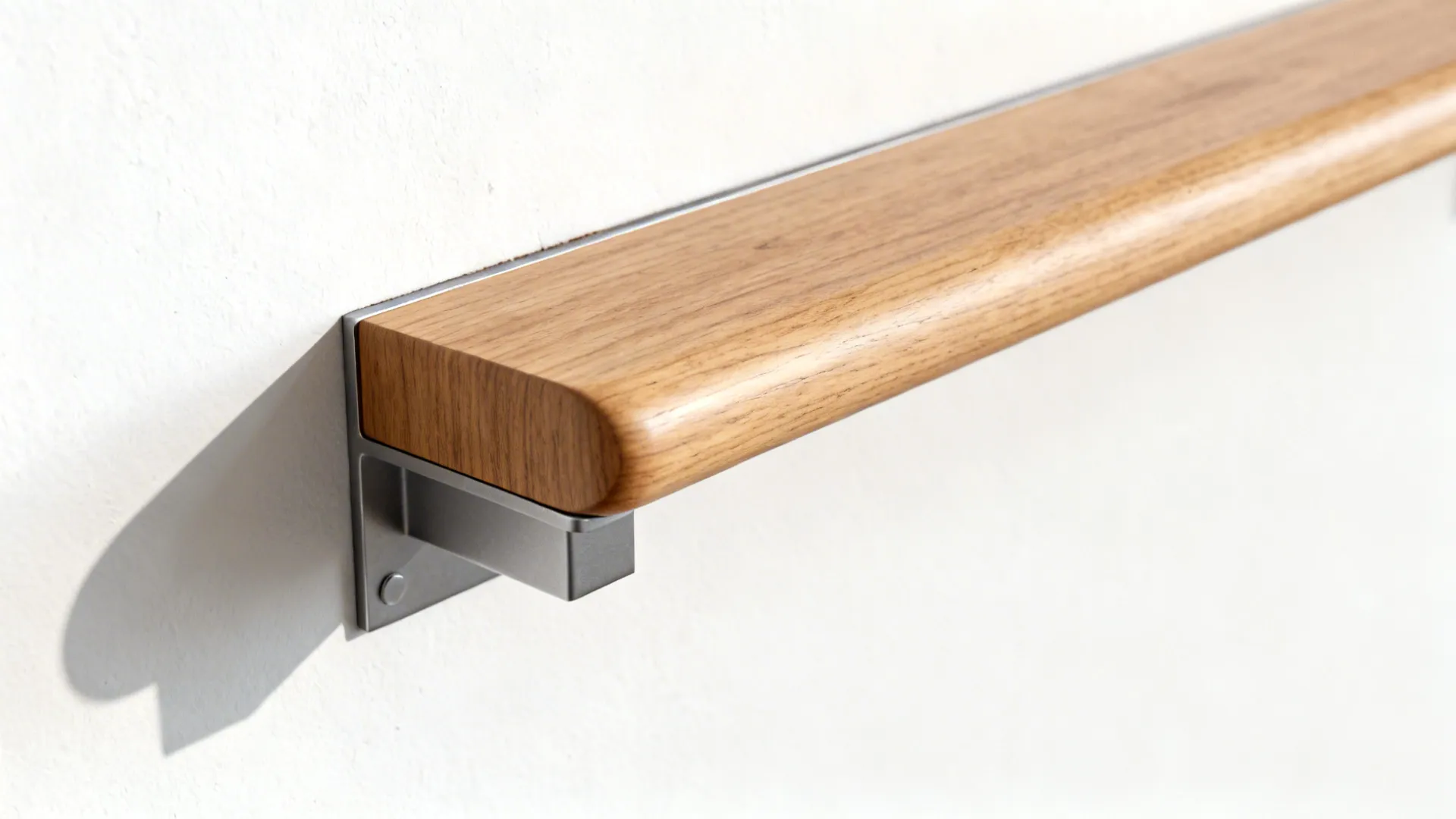 Wooden handrail mounted on white wall using silver metal bracket with a soft grey shadow