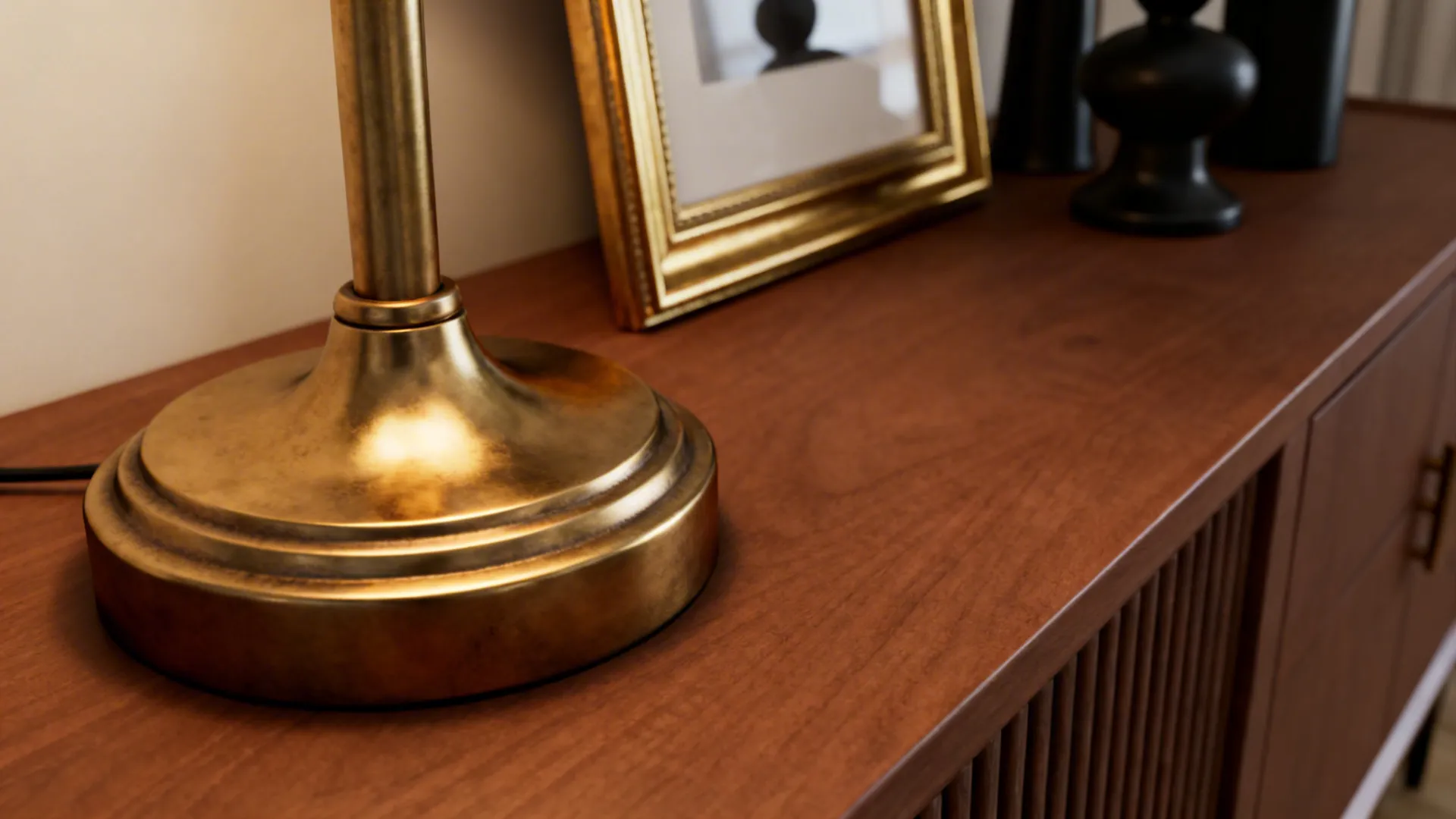 Brushed brass lamp and picture frame positioned near a brown console and black fixtures.