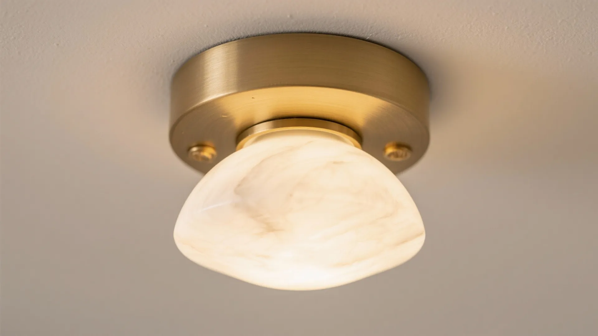 Macro view of brushed brass with an alabaster-style diffuser emitting a soft, warm glow.