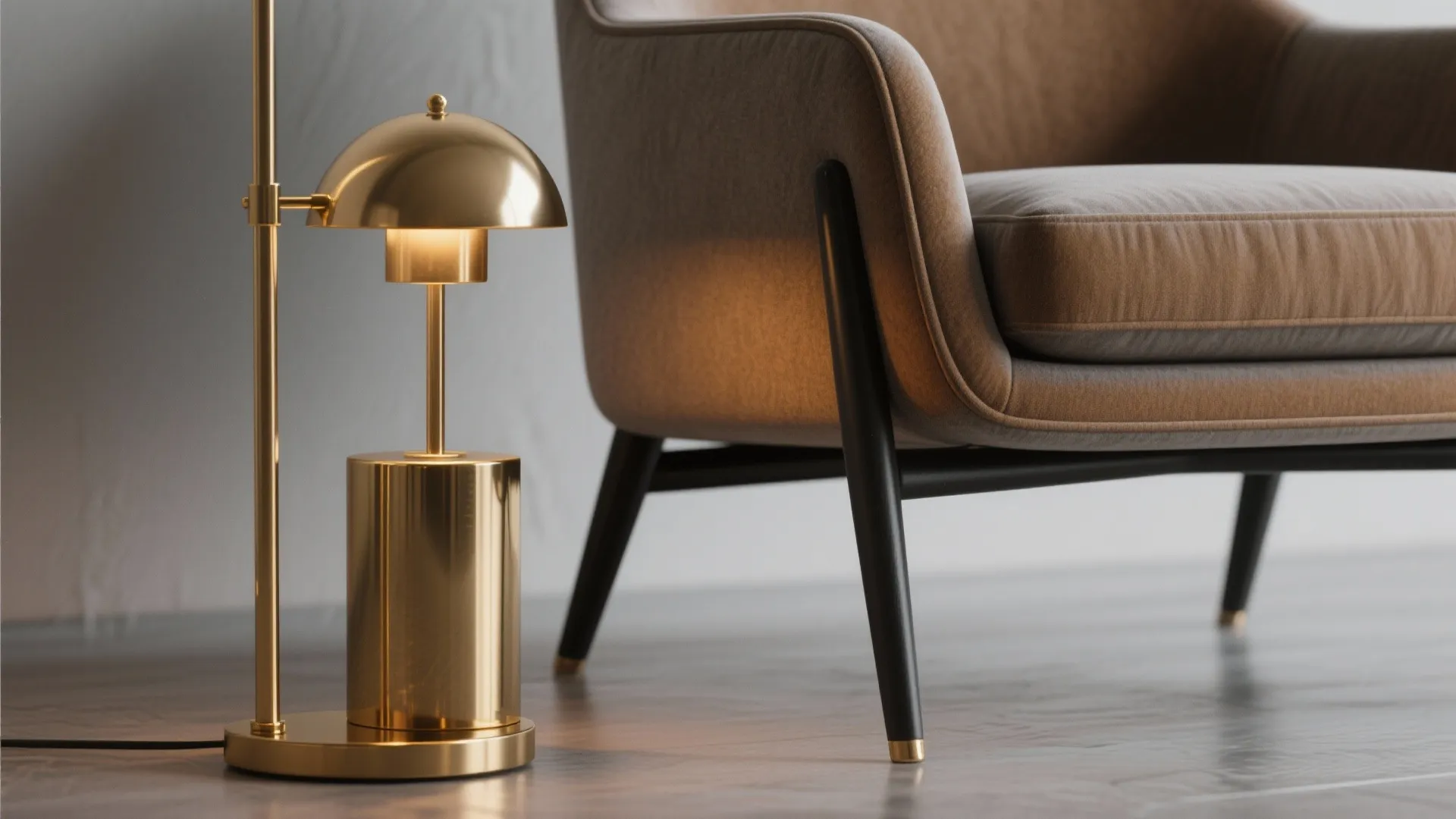 Modern gold table lamp standing next to a brown armchair on a polished wooden floor surface