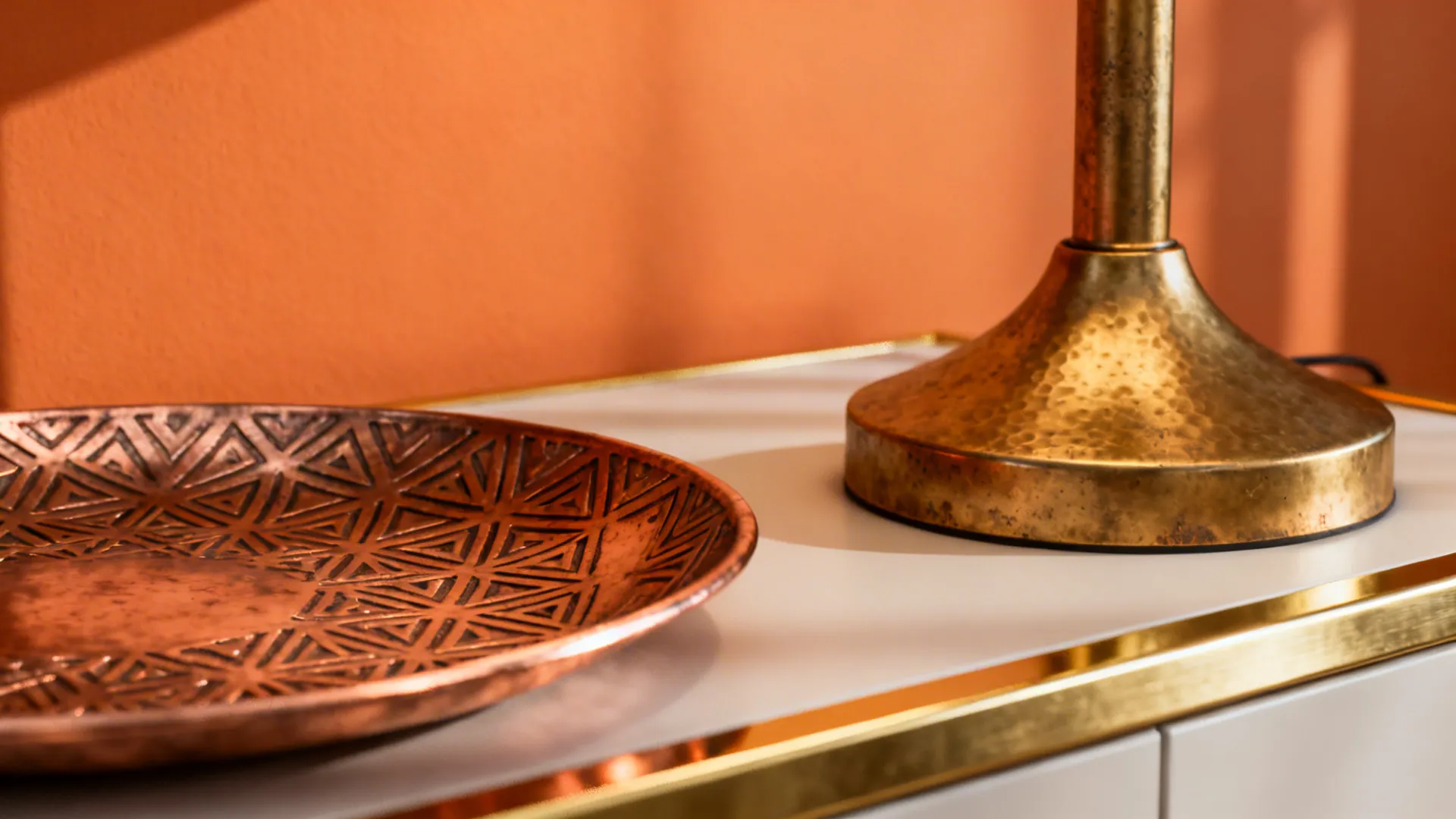 Matte brass and copper accents warming an orange accent wall