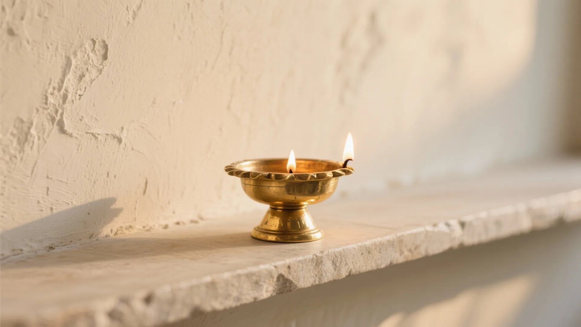 Close up view of a small brass light with burning flame on stone shelf ledge