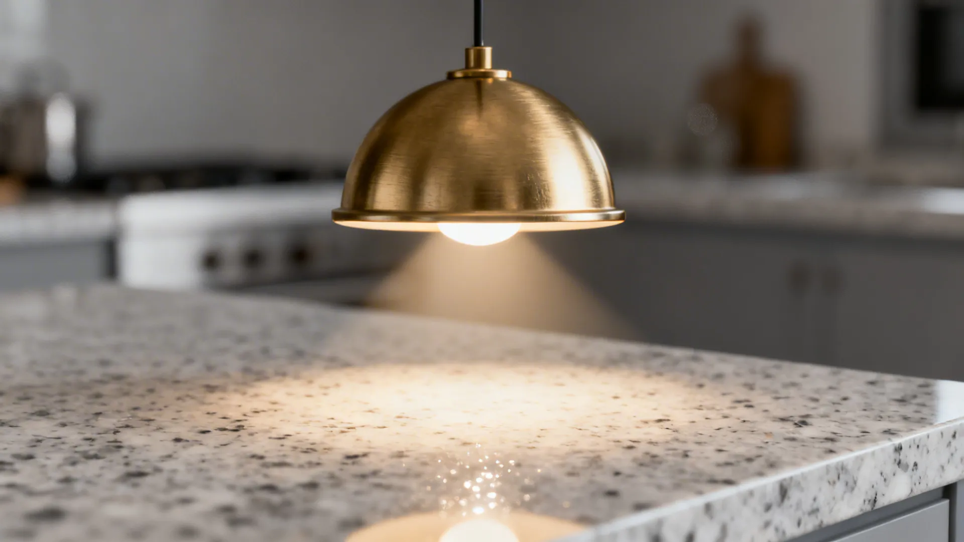 Close up of a gold dome ceiling light hanging above a grey and white marble countertop