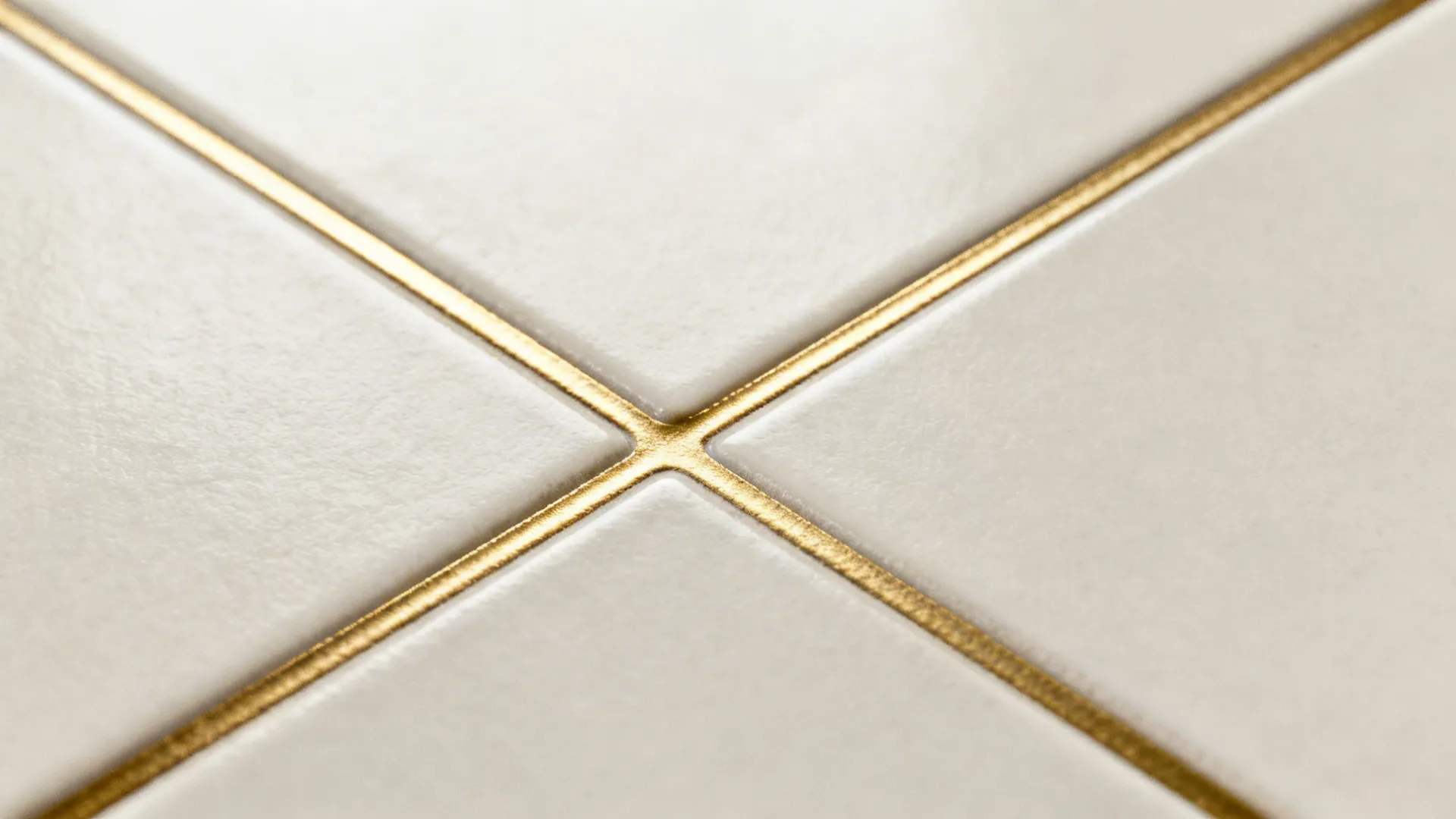 Macro of a thin brass inlay set flush within matte porcelain floor tiles.