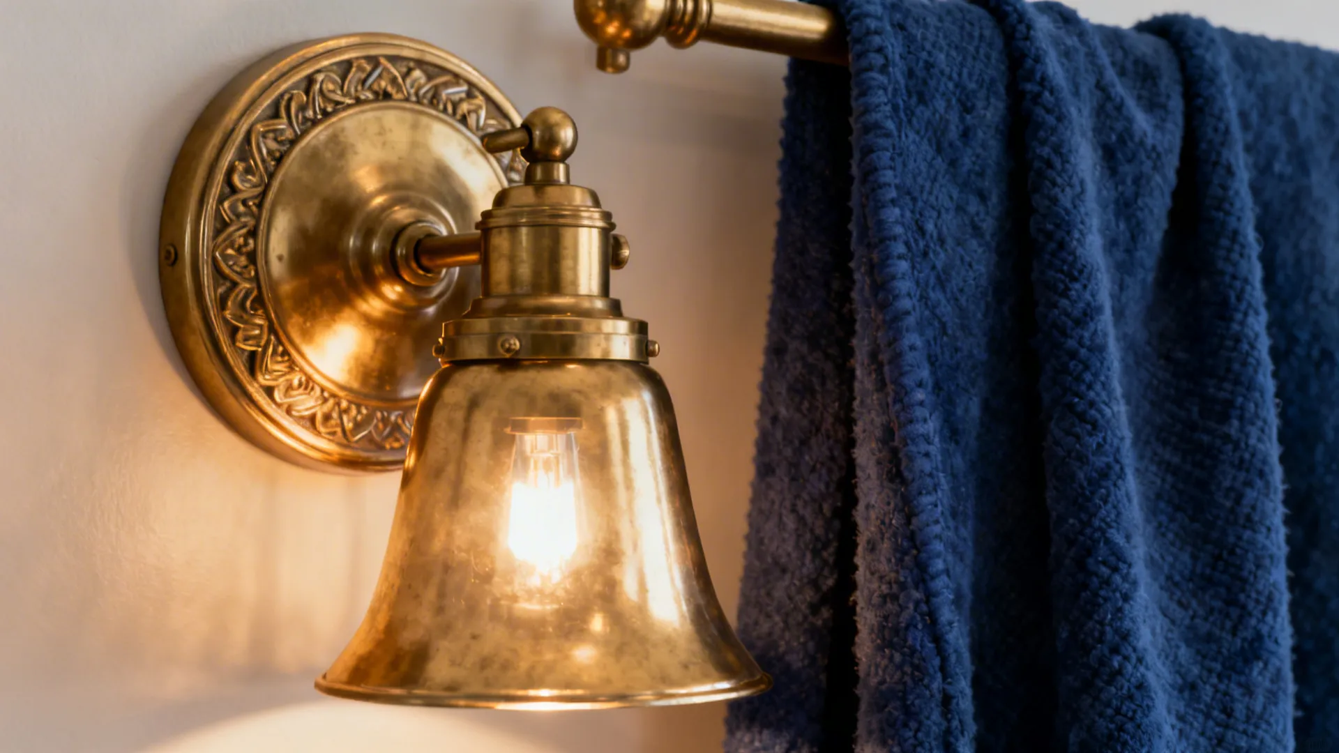 Brass wall sconce beside a deep blue throw creating warm contrast