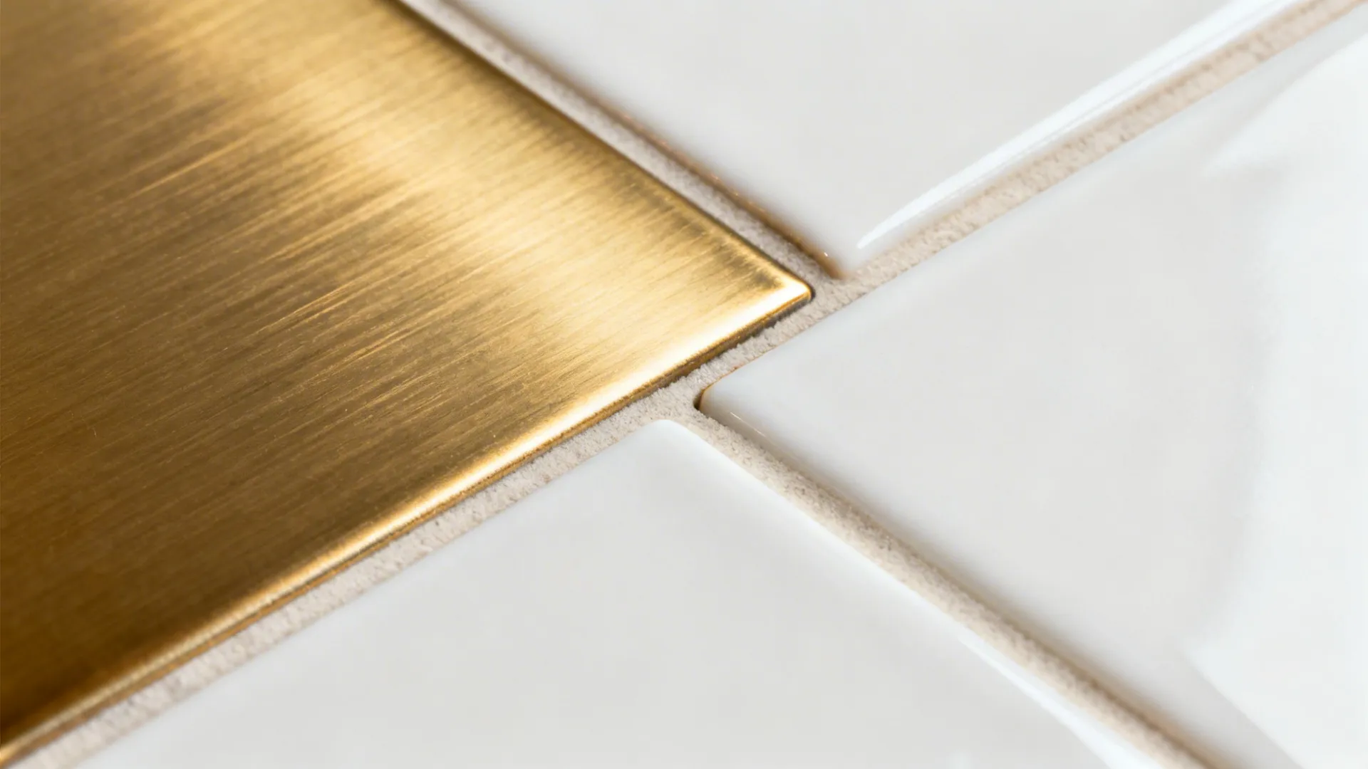 Macro of brushed-brass liner meeting white ceramic tile with clean grout and precise cuts.
