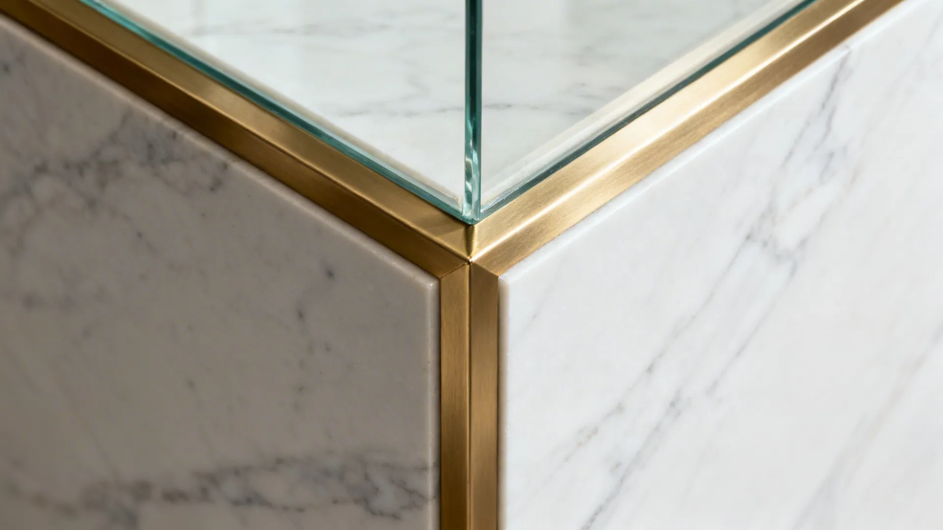 Macro of brushed brass frame junction with clear glass and porcelain slab veining.