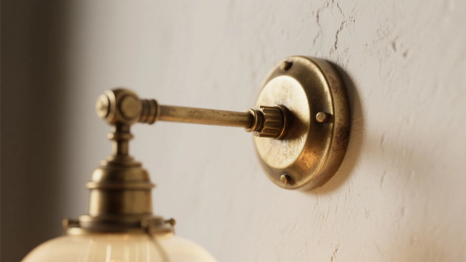 Close up view of a brass wall light fixture base mounted on a textured wall