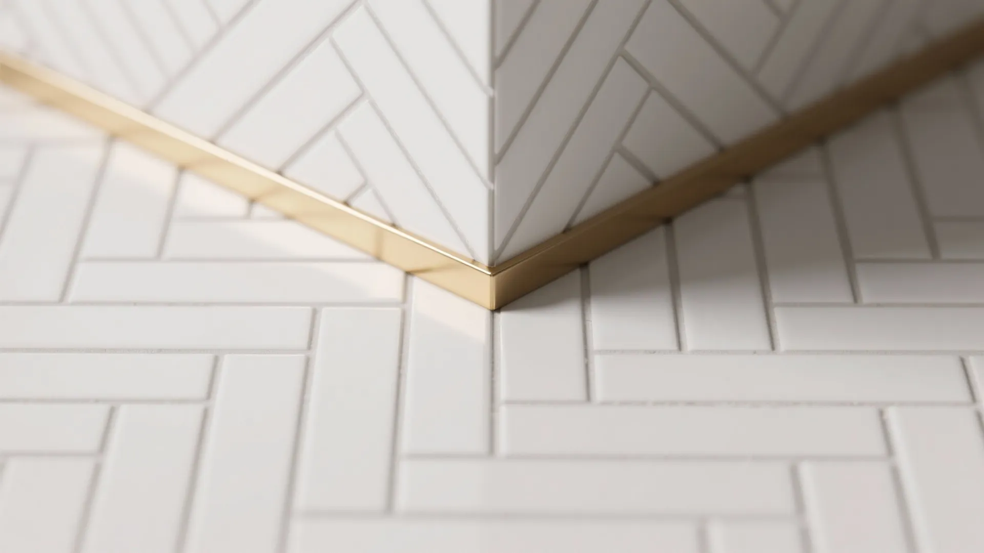 Close-up of white herringbone tiles with thin brass trim showing precise installation.