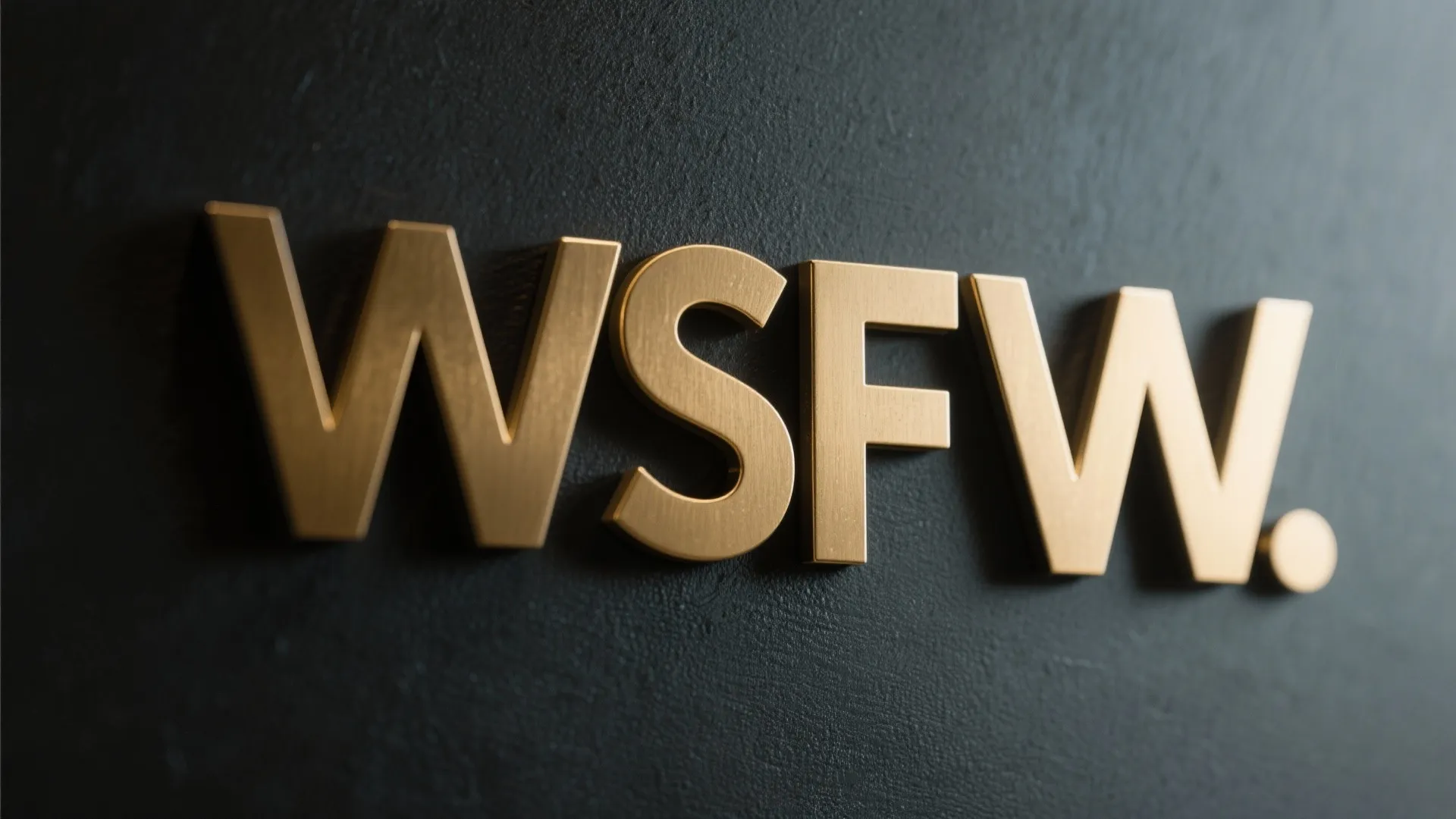 Brushed brass bathroom sign letters on matte dark wall