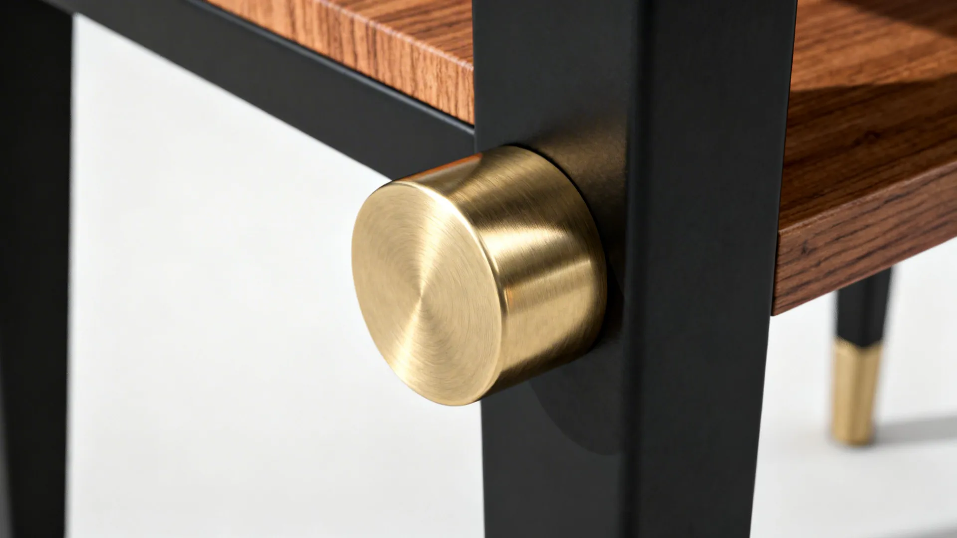 Macro detail of a brass-capped table leg with walnut shelf and matte black finish.