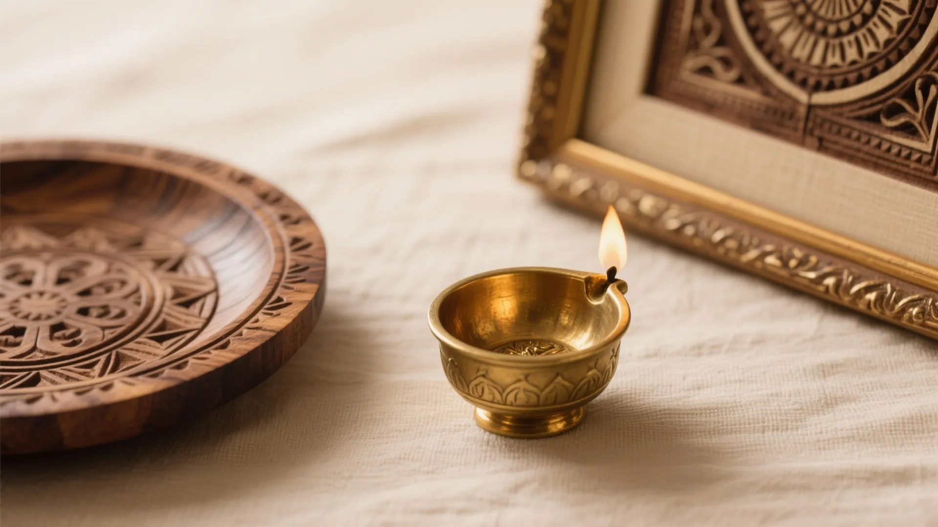 Small brass candle holder with a burning flame near a carved wooden plate and frame