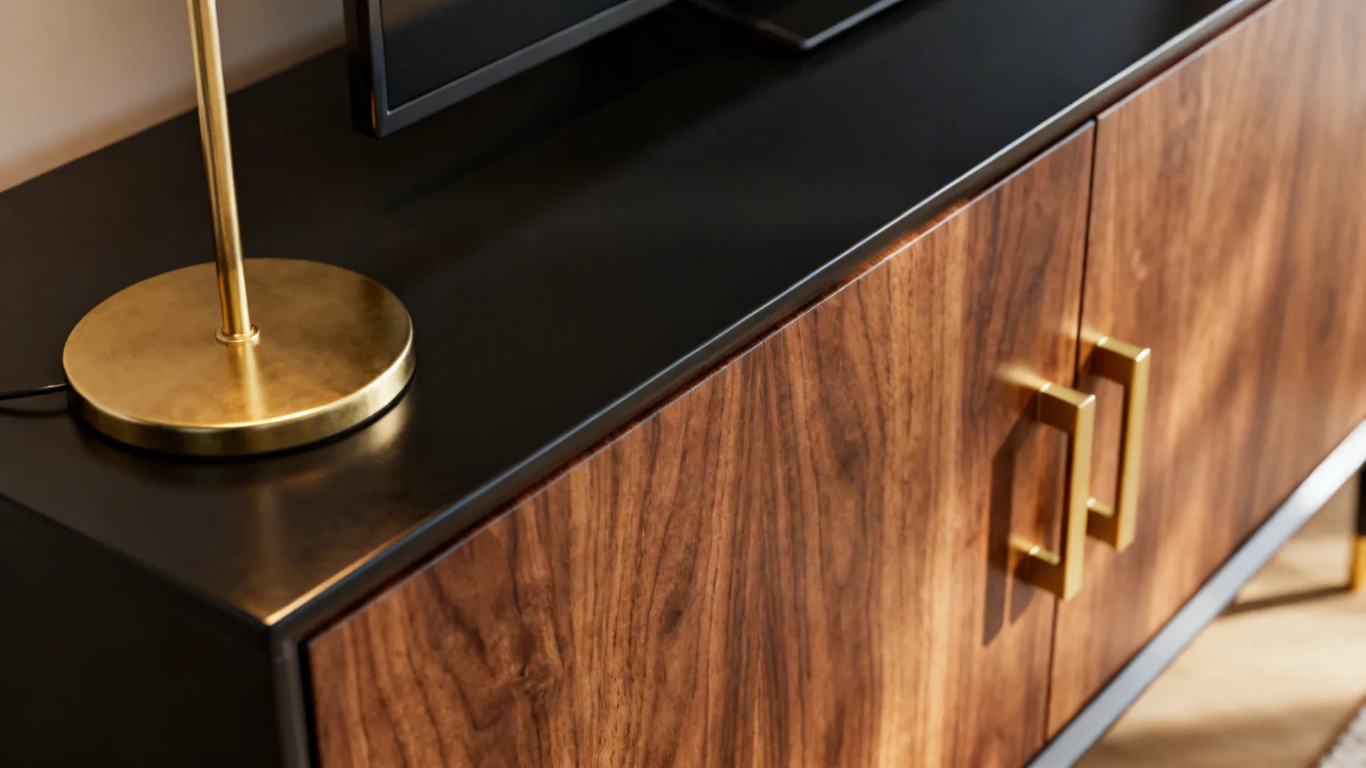 Brass lamp and walnut console details against black furniture