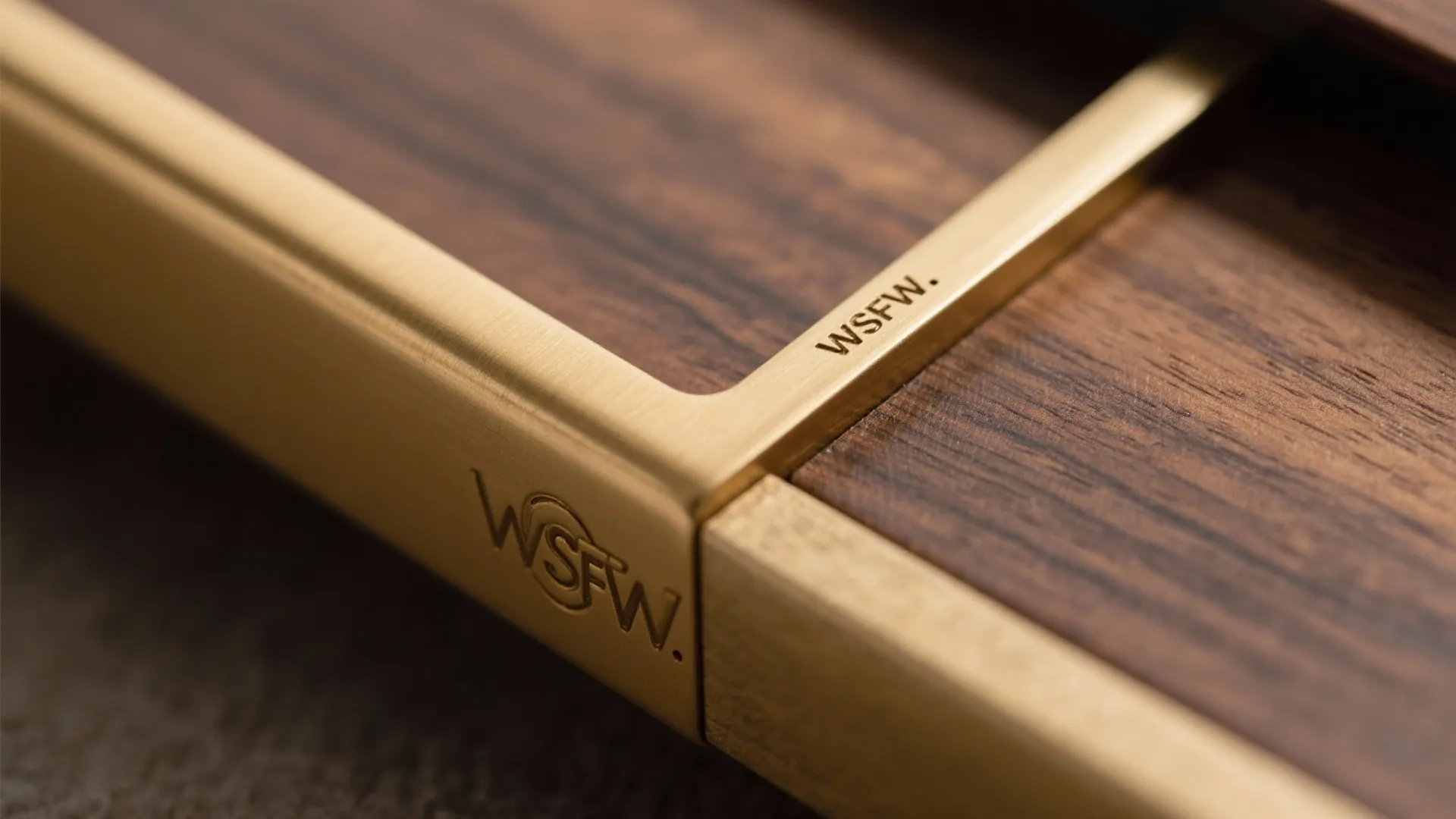 Macro of brass profile meeting walnut veneer with precise, flush detailing.