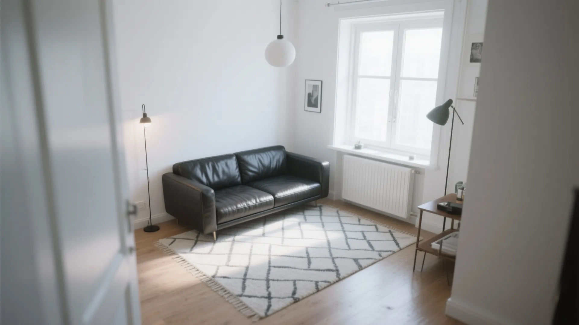 Small white room featuring black leather sofa patterned rug ceiling light and natural window light view