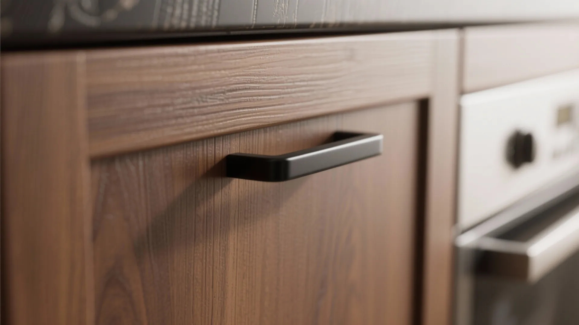Close up of brown wood cabinet door with modern black handle next to white oven