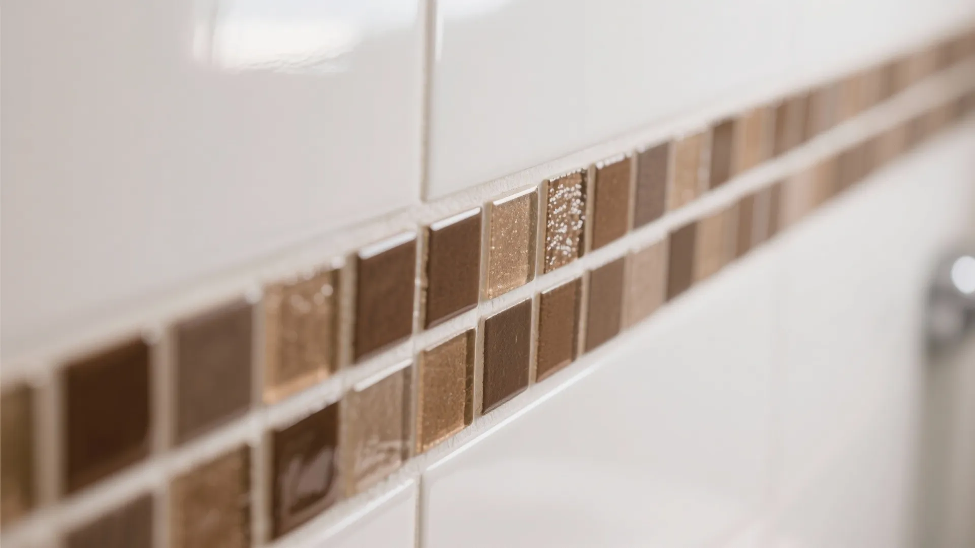 Close up of brown and beige mosaic tiles used as a border on white wall