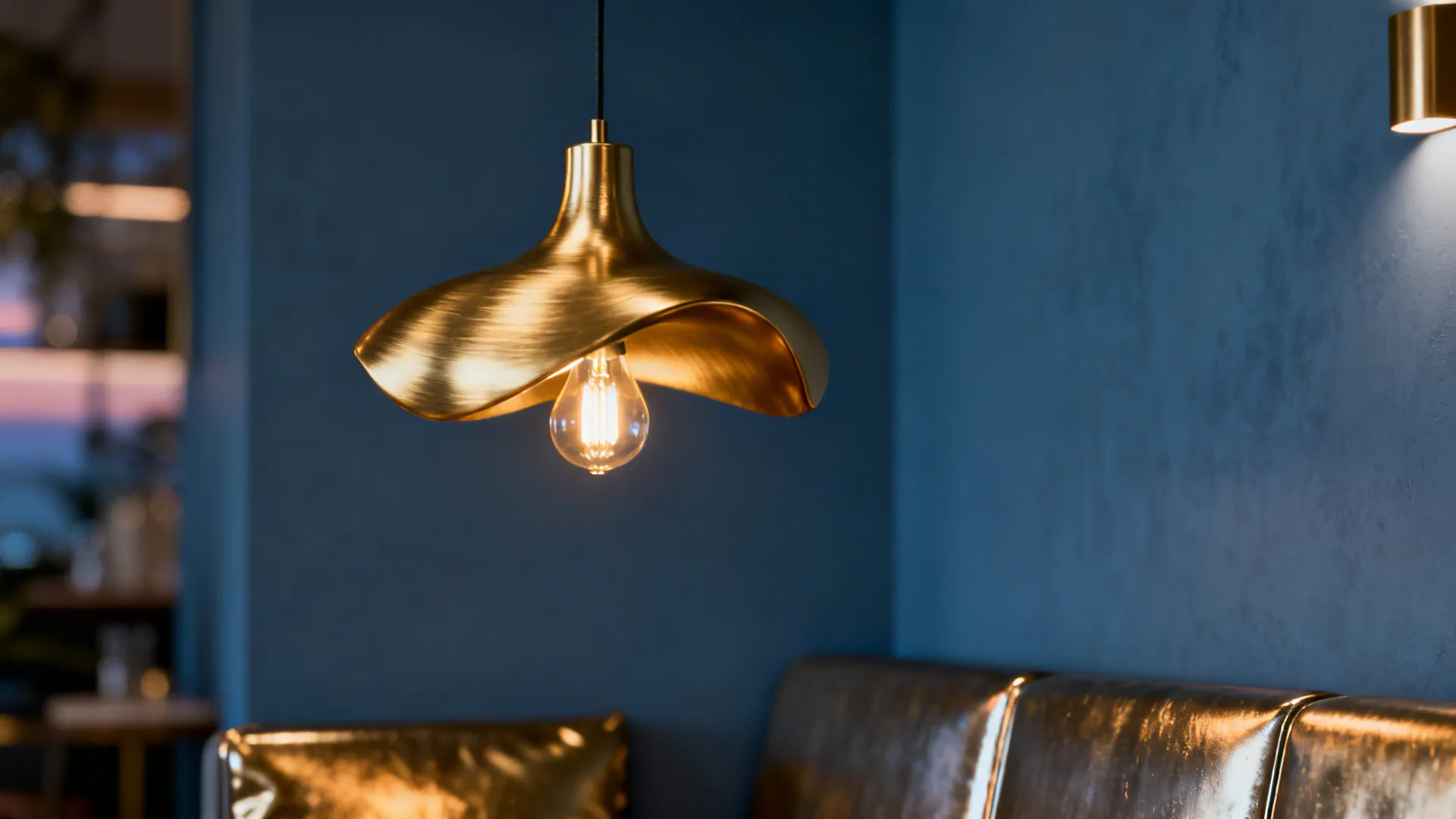 Brushed-gold sculptural pendant casting warm light in a blue-grey living room.