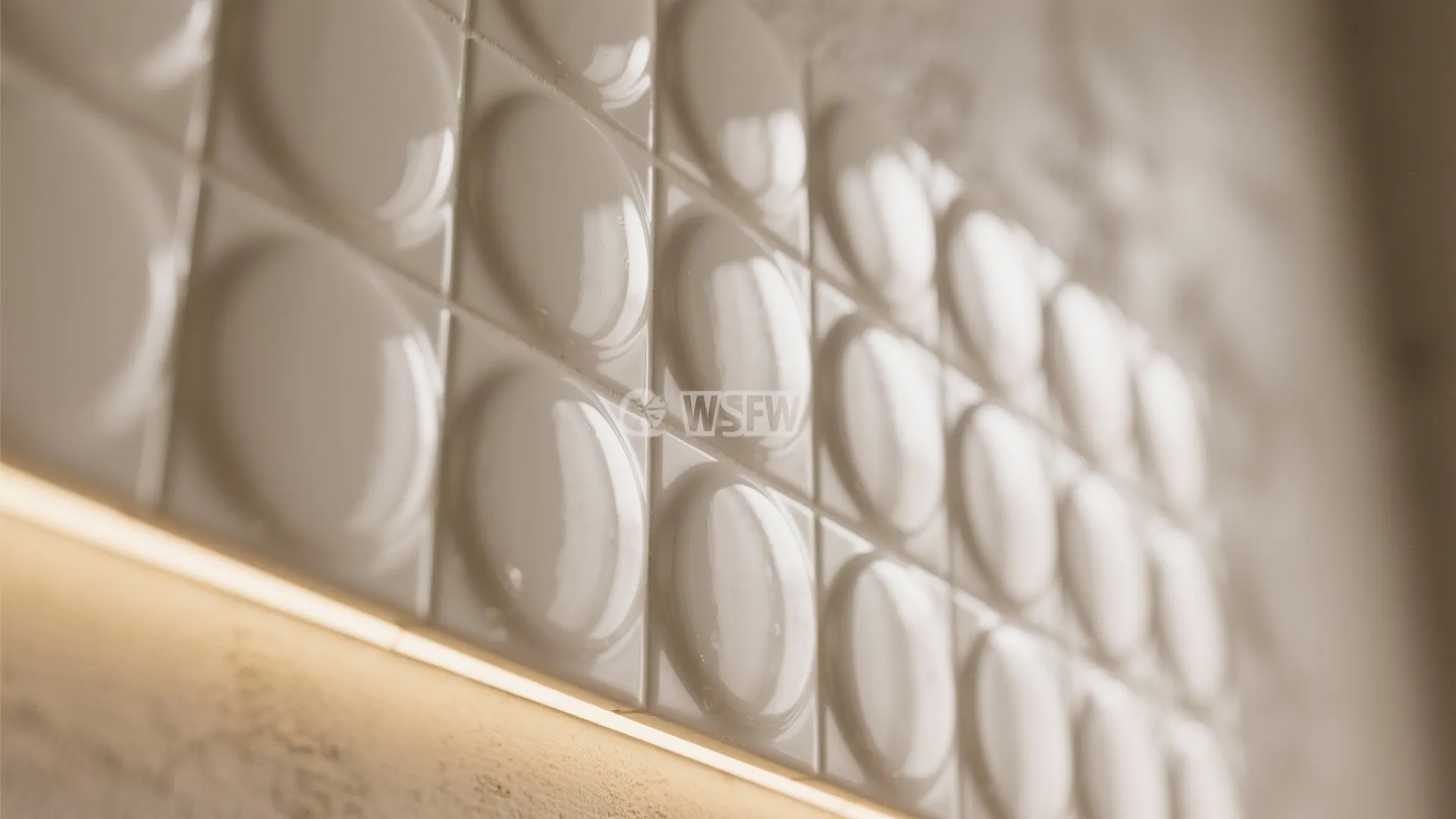 Close up view of white bubble wall tiles with warm light fixture shining from below